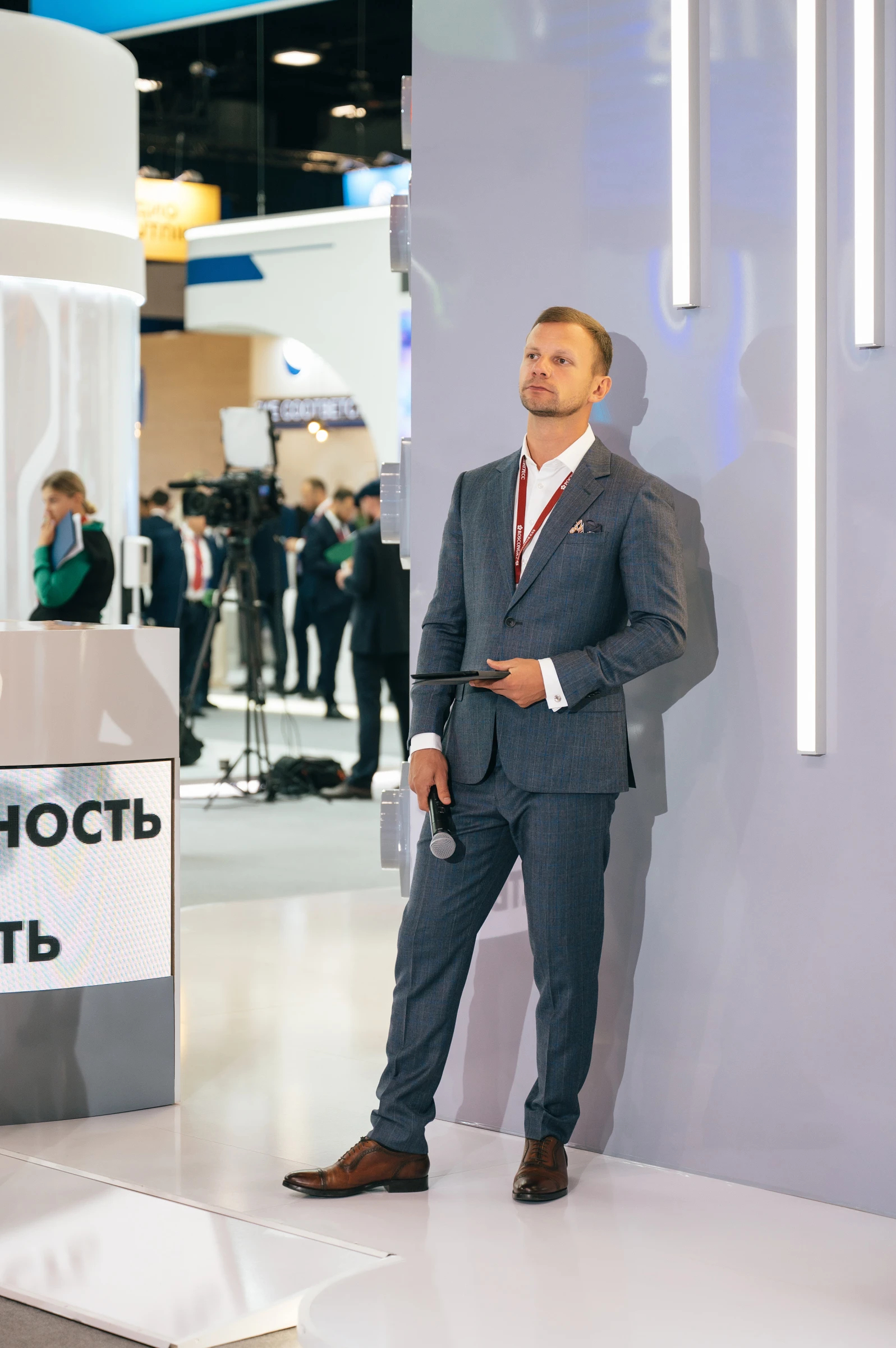 Мужчина с микрофоном стоит рядом с телевизионной камерой