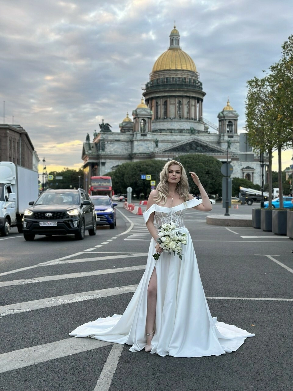 свадебное платье с корсетом и локоны невесты с букетом роз у собора