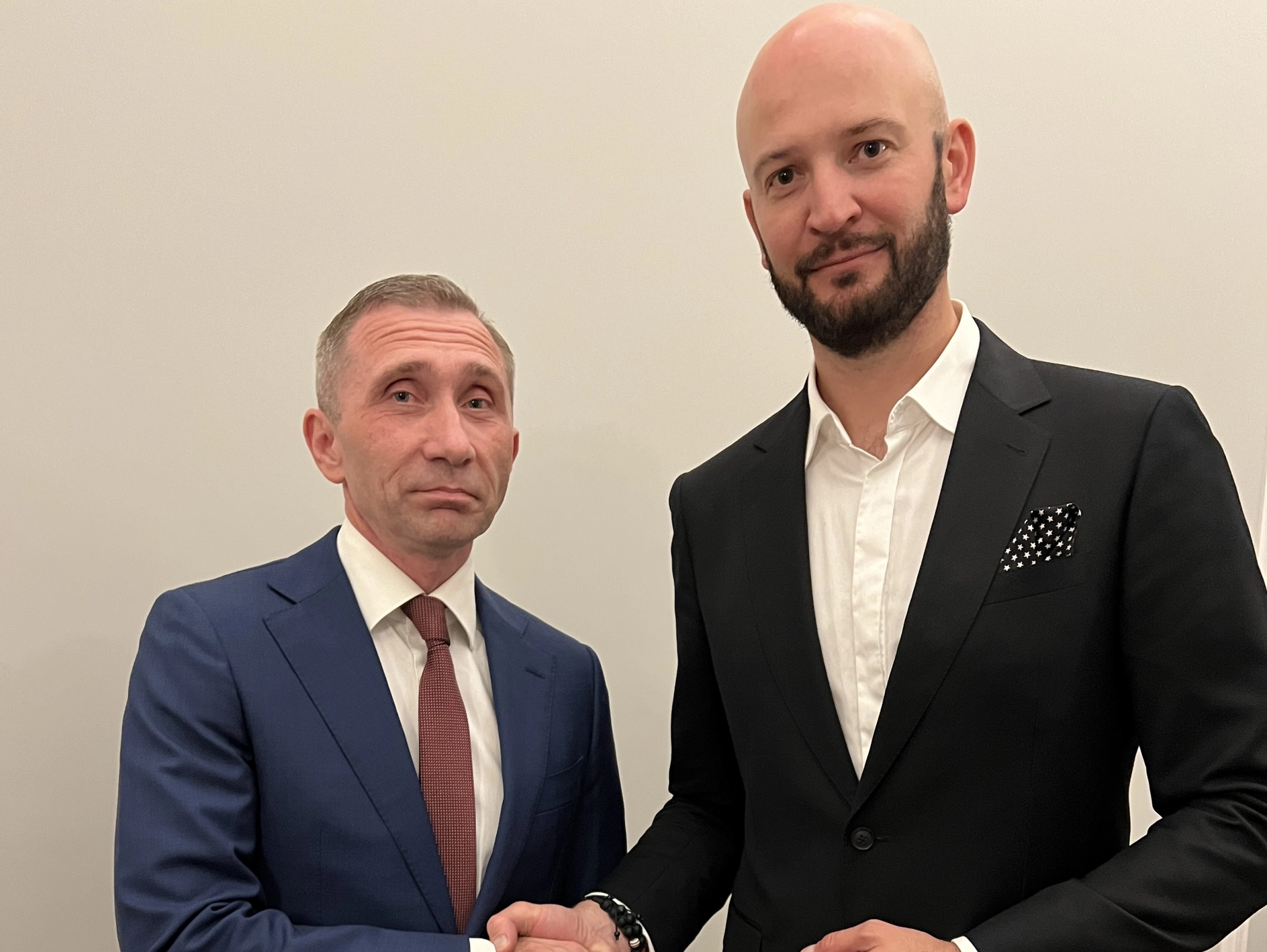 Двое партнёров в деловых костюмах скрепляют сделку крепким рукопожатием