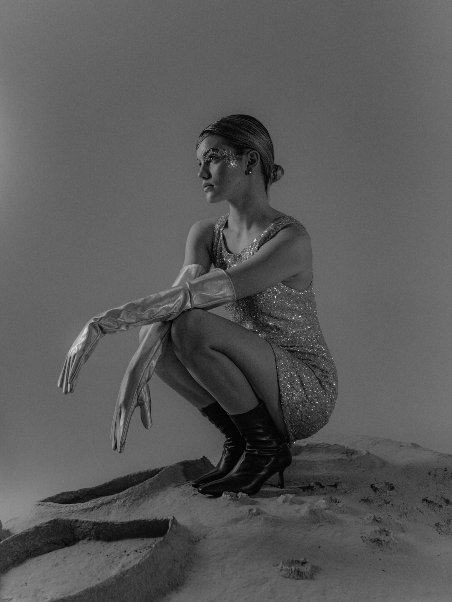 блестящее мини-платье с атласными перчатками и причёской на песчаном фоне