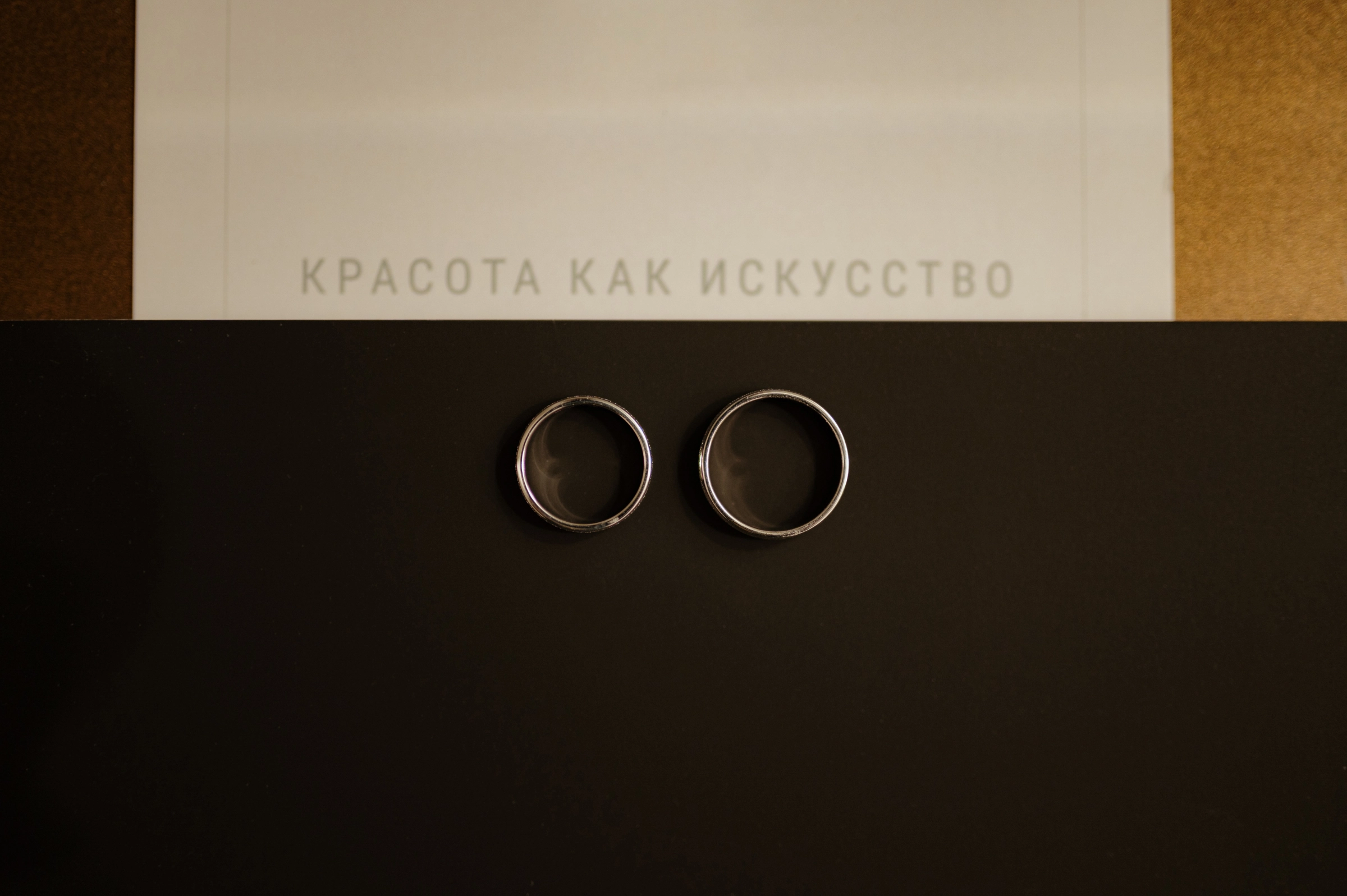 два обручальных кольца на чёрной поверхности рядом с карточкой с надписью