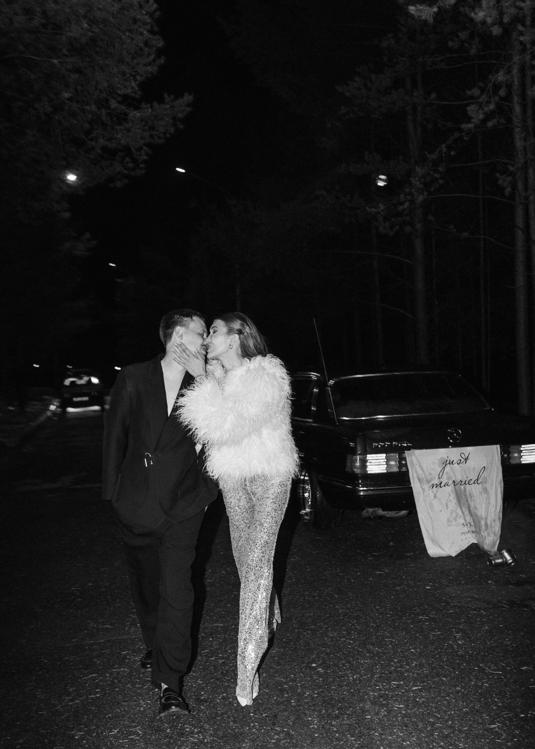 молодожёны целуются ночью у ретро автомобиля с табличкой just married