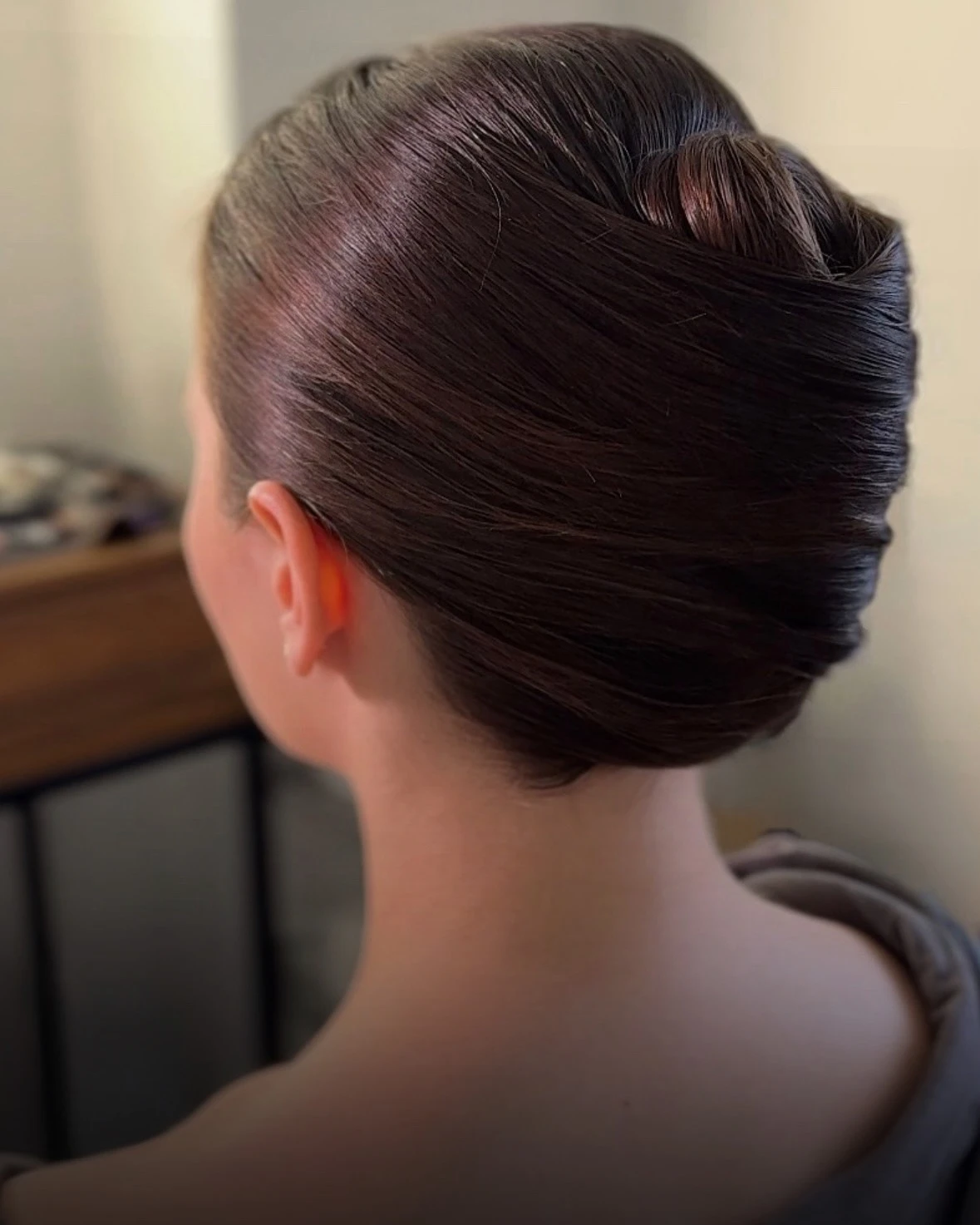 Тёмные волосы аккуратно уложены в гладкий низкий пучок сзади