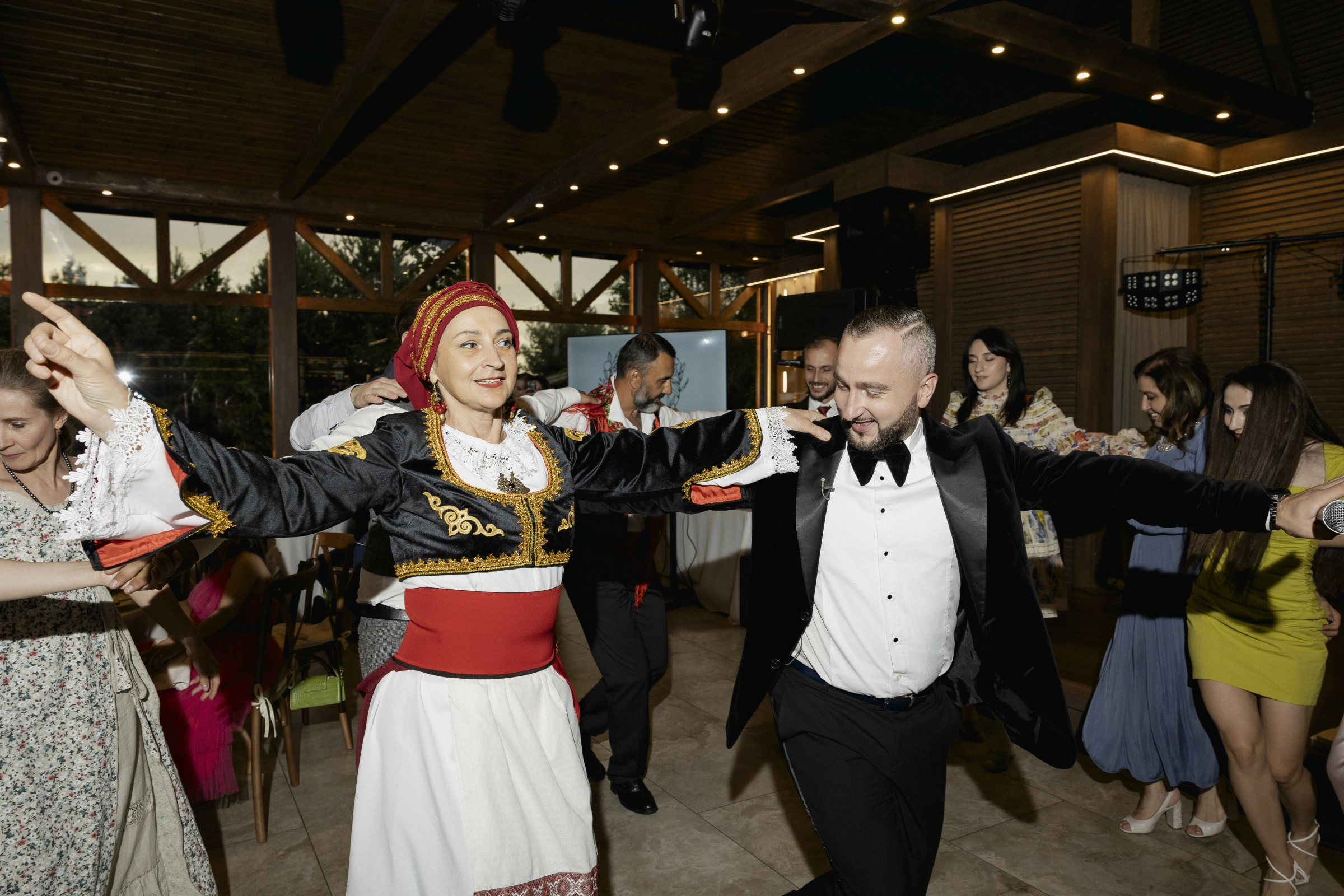 Пара танцует традиционный танец в ресторане с гостями