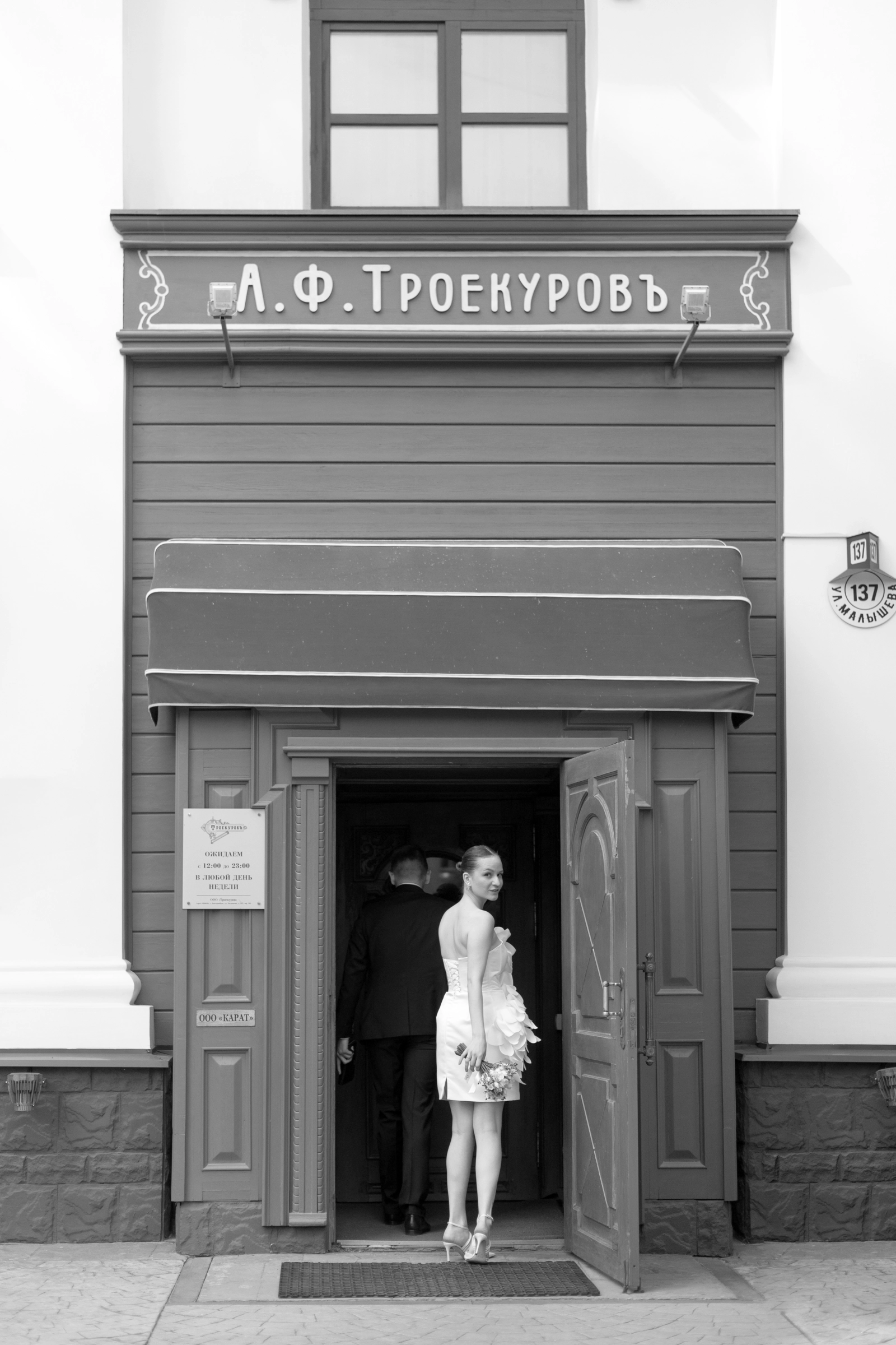невеста в коротком платье у входа в старинное здание ресторана