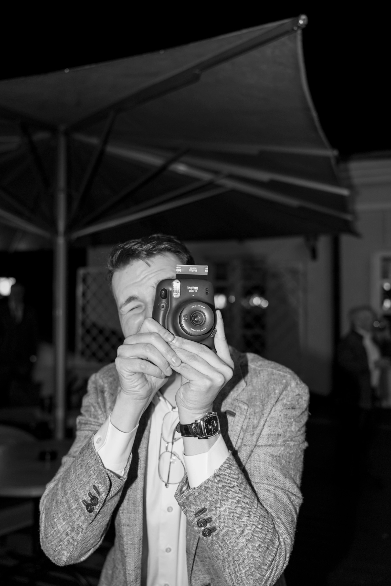 Мужчина снимает на плёночный фотоаппарат под уличным зонтом