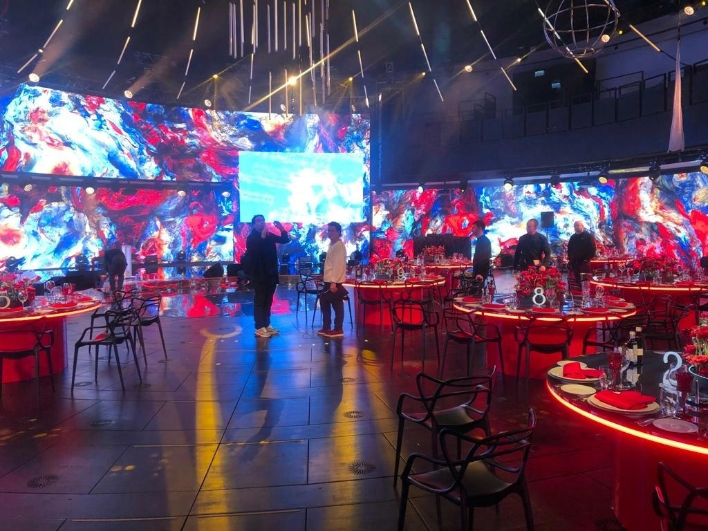 Круглые столы с красной подсветкой на фоне абстрактных LED-экранов