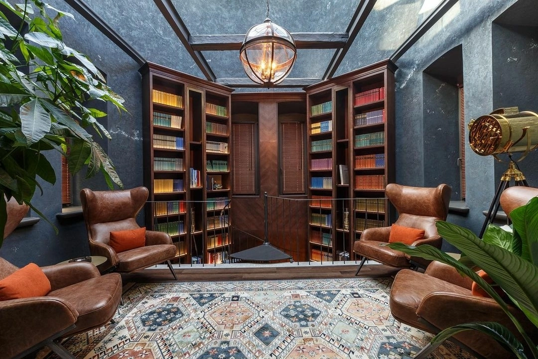 кожаные кресла и книжные стеллажи в кабинете со стеклянным потолком