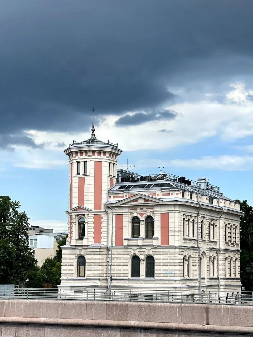 историческое здание особняка с угловой башней на фоне грозового неба