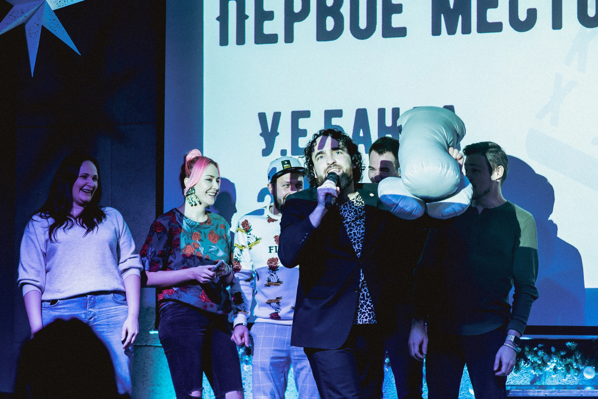 ведущий и команда победителей позируют на сцене корпоратива