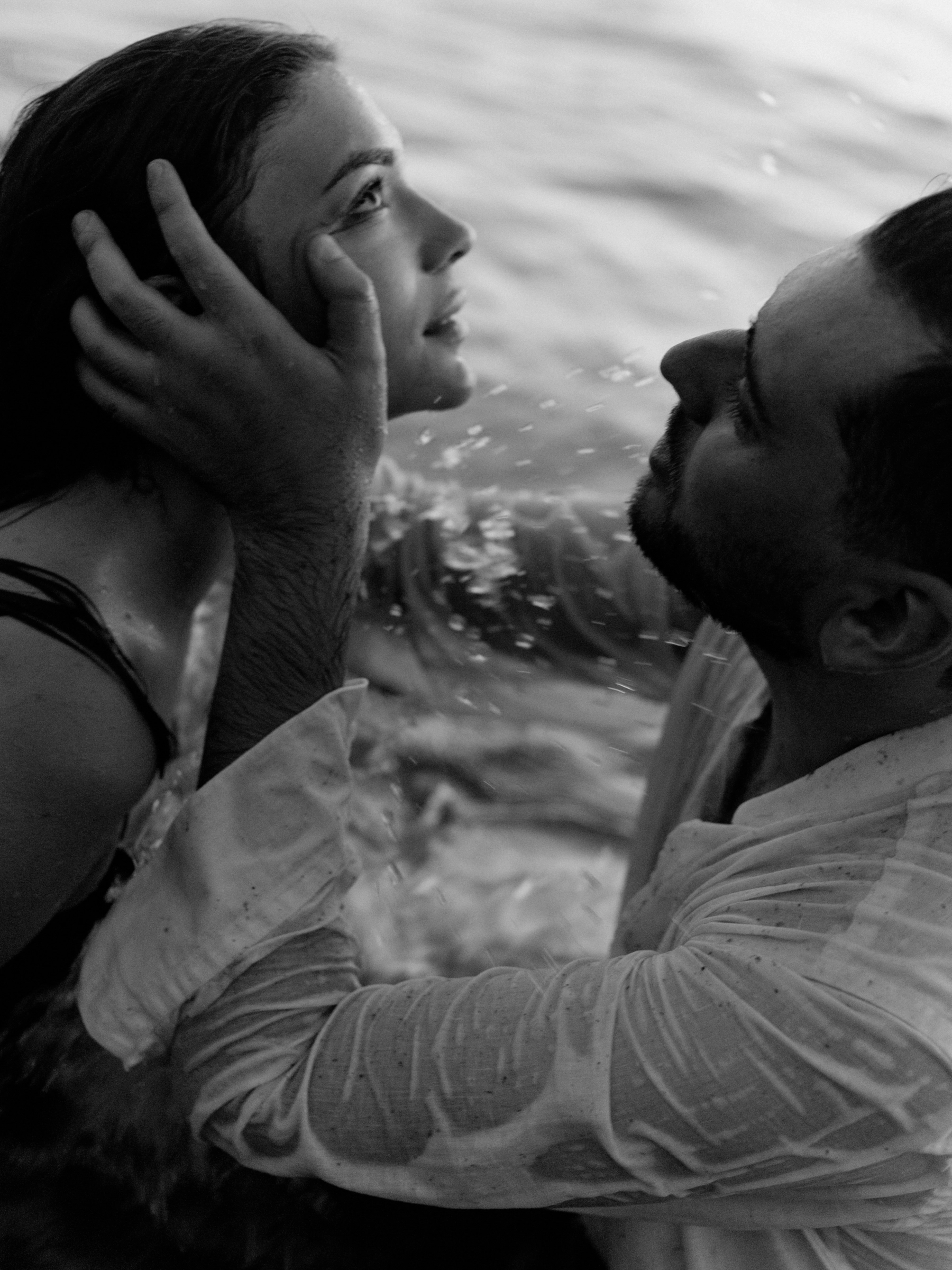 Пара обнимается стоя в воде во время love story на побережье