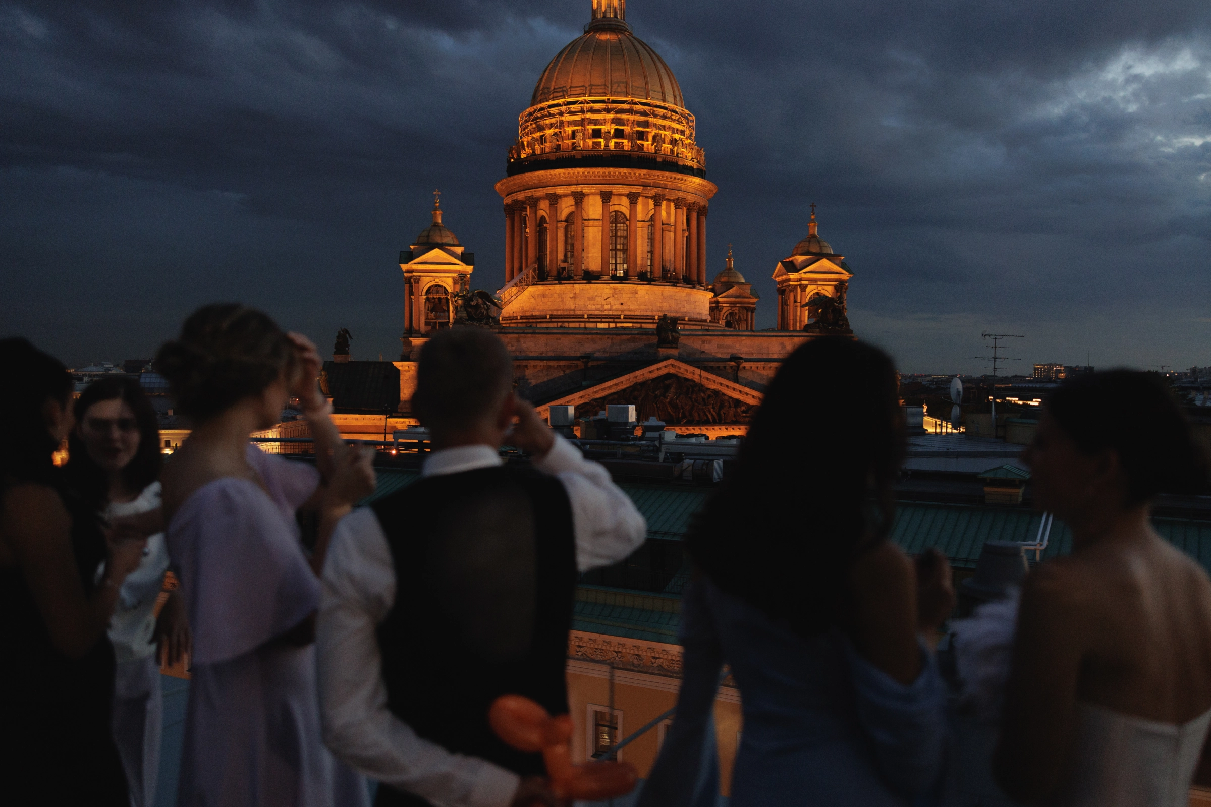 силуэты гостей на террасе вечером на фоне подсвеченного купола собора