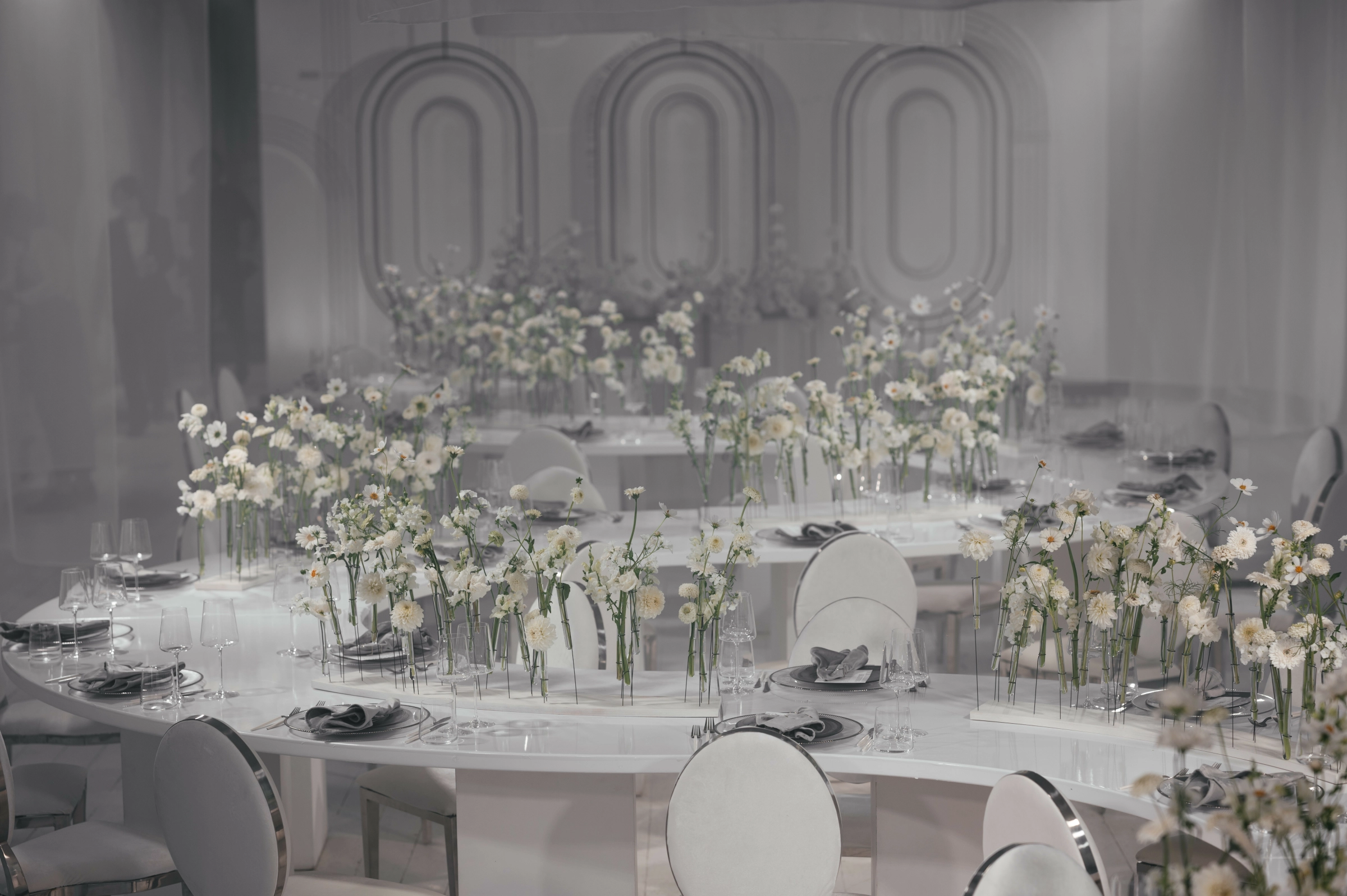 банкетные столы с ромашками на фоне светлых арочных декораций зала
