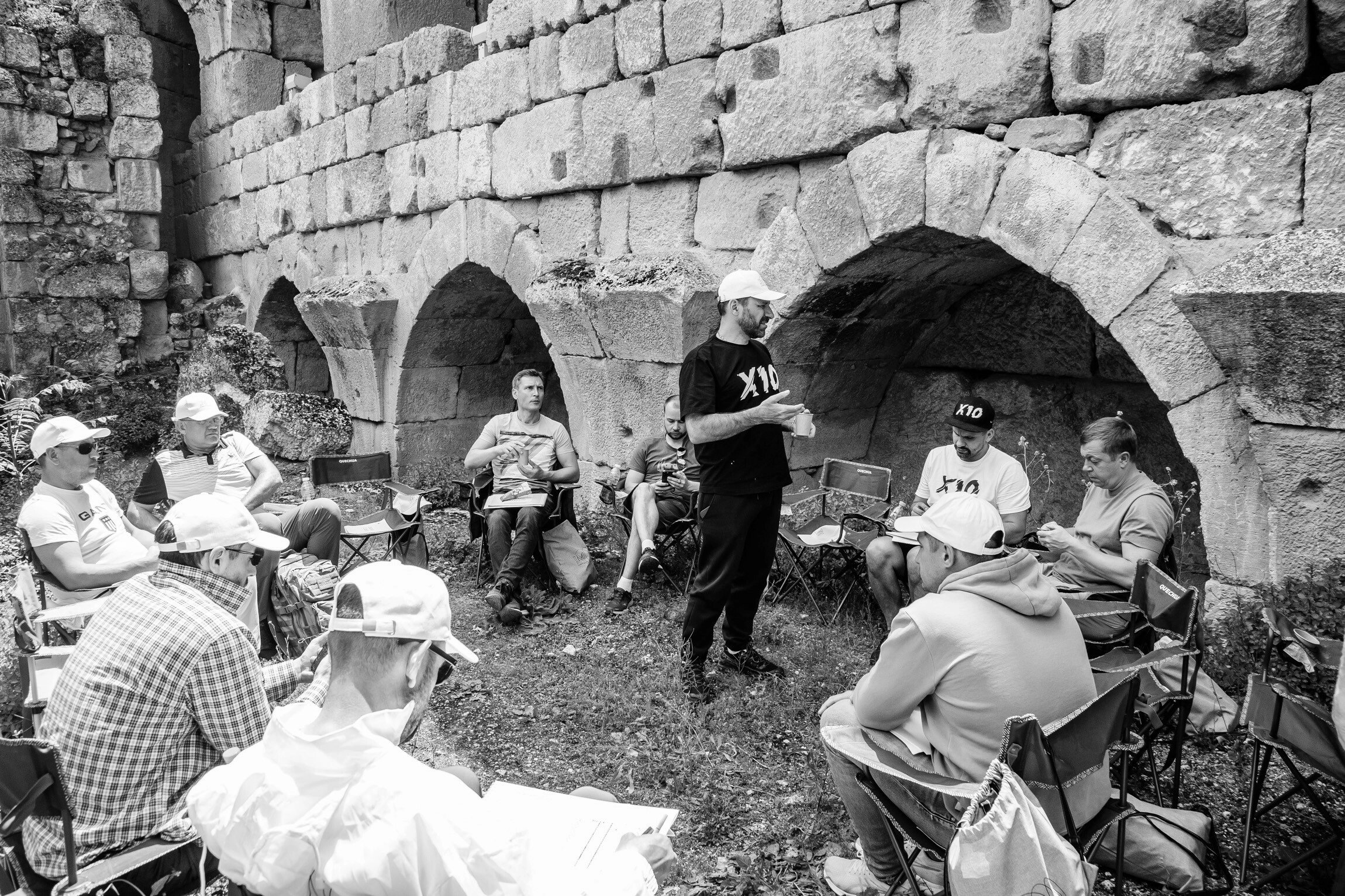 участники деловой встречи сидят кругом среди старинных арок