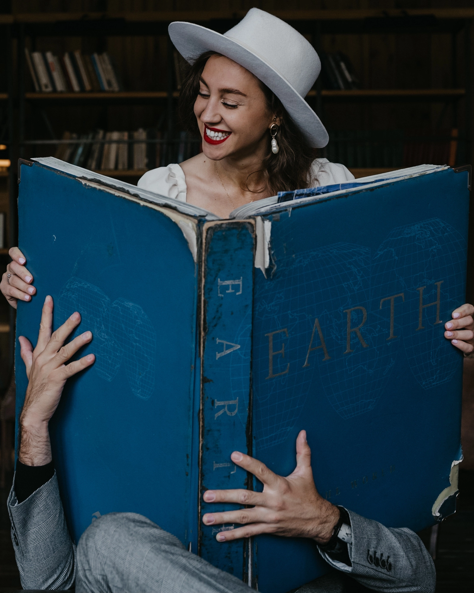 жених и невеста листают гигантскую книгу в домашней библиотеке