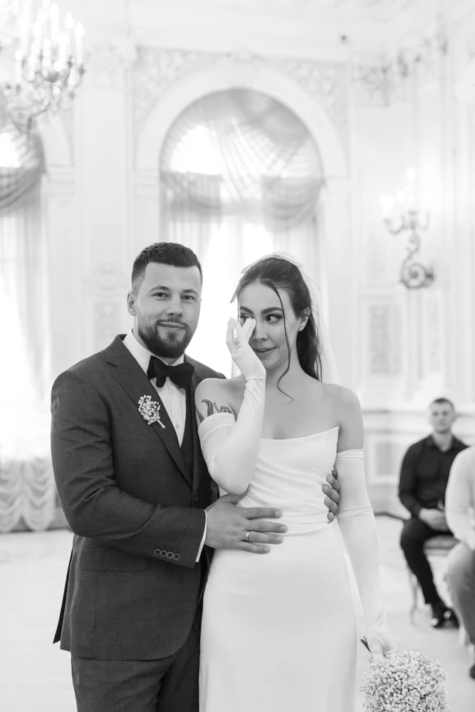невеста вытирает слёзы радости рядом с женихом в парадном зале