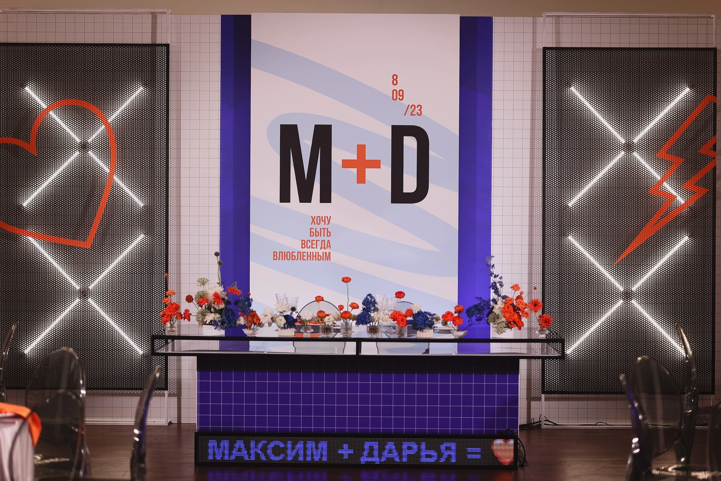 президиум с монограммой M+D, неоновым сердцем и молнией на синем фоне с цветами