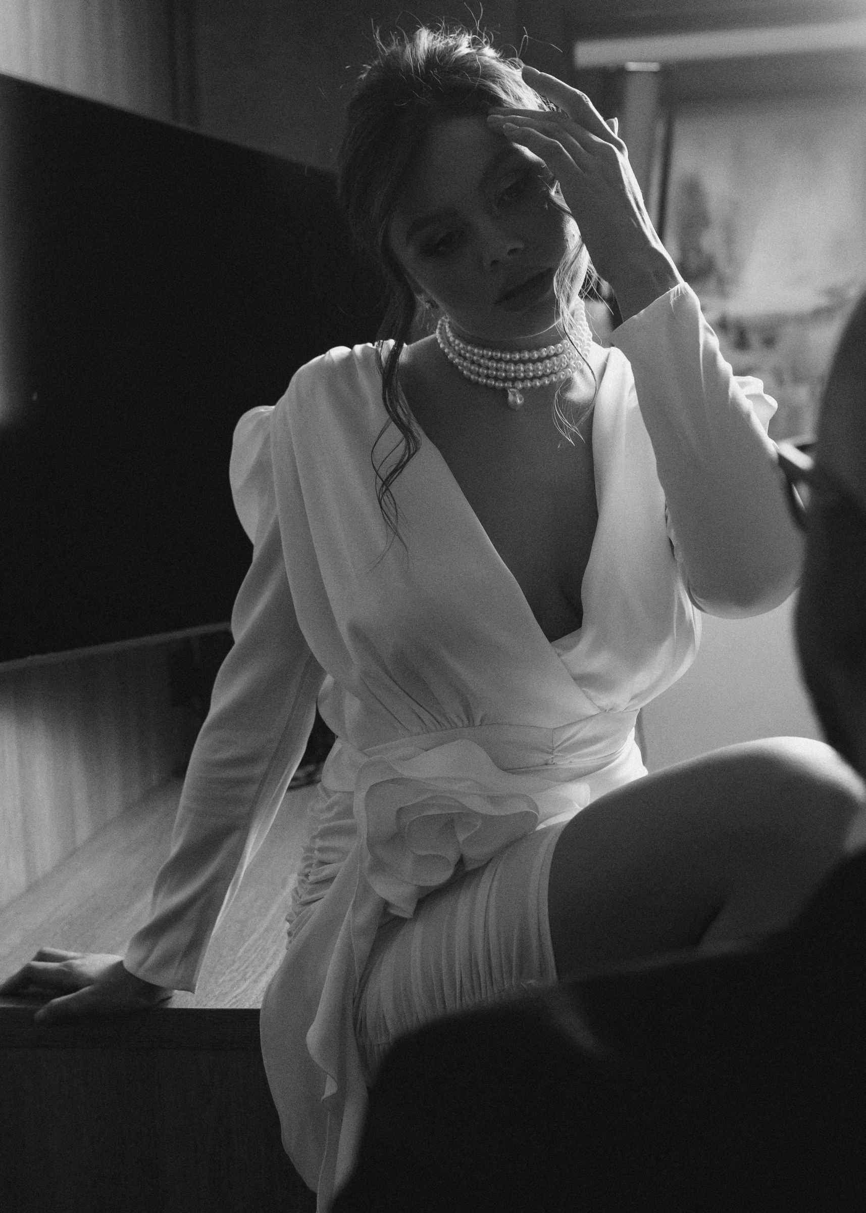 девушка в белой блузе с жемчугом сидит в мягком свете у окна