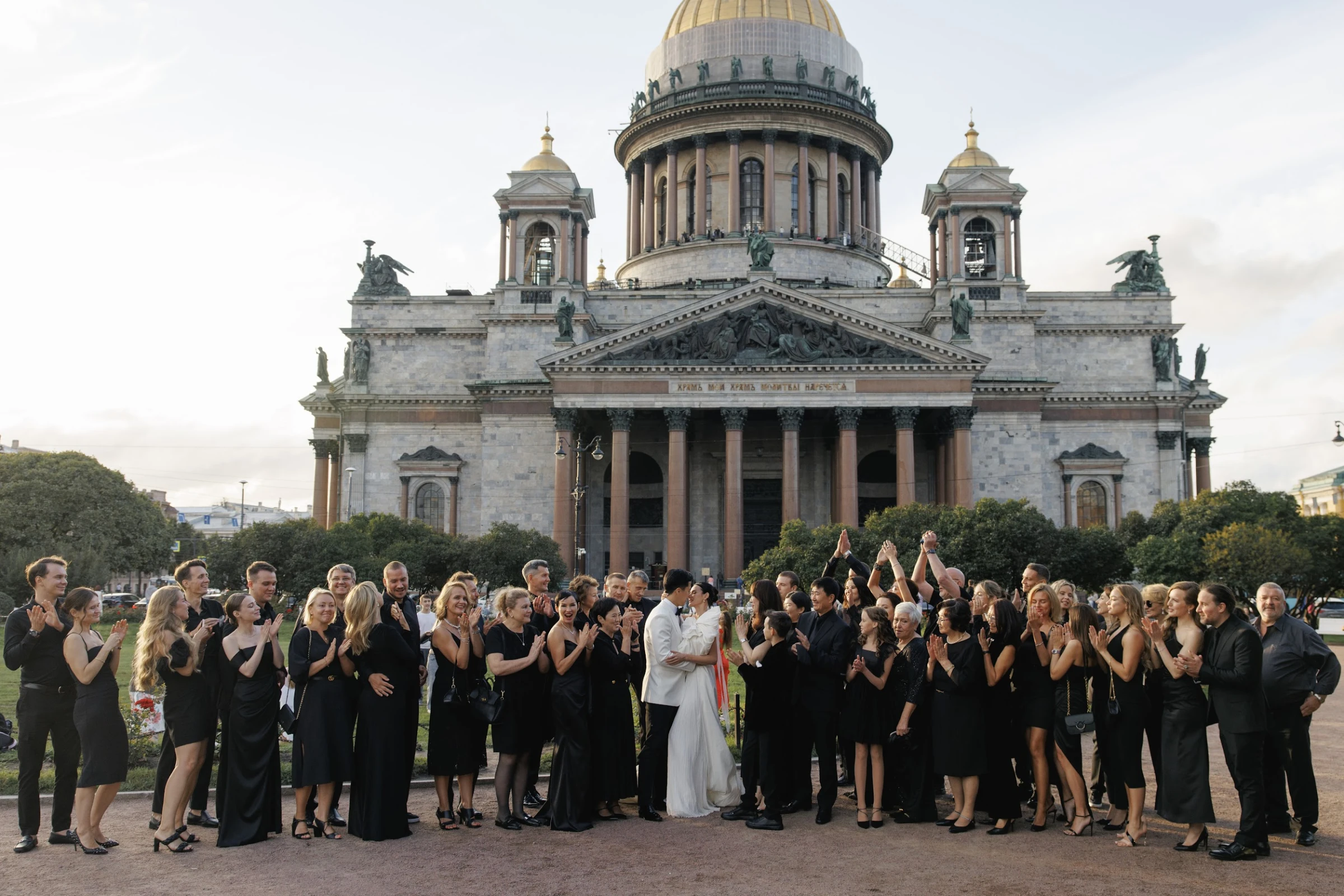молодожёны с гостями на фоне купола собора в центре города вечером