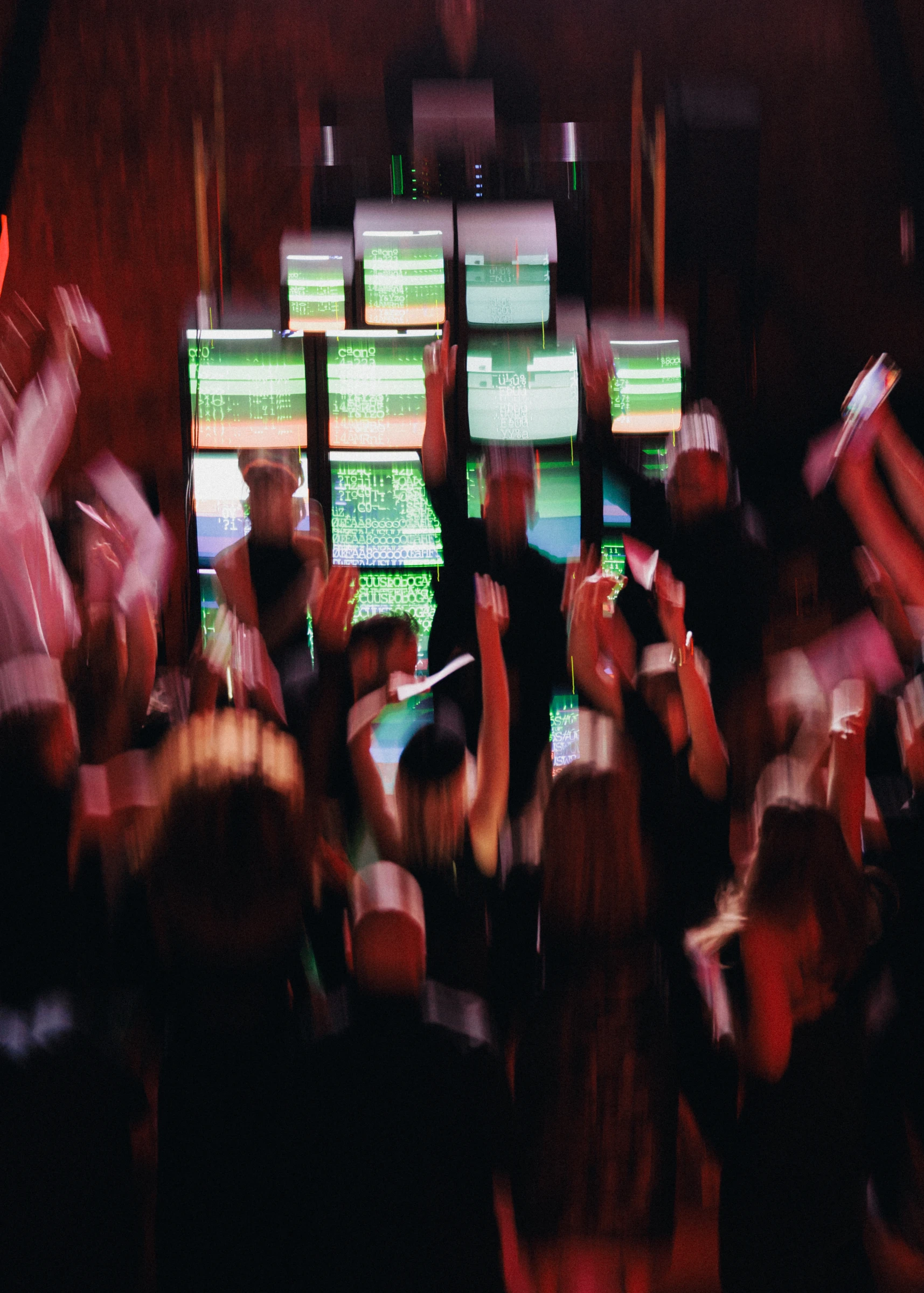 Размытые силуэты танцующих гостей на фоне зелёных экранов
