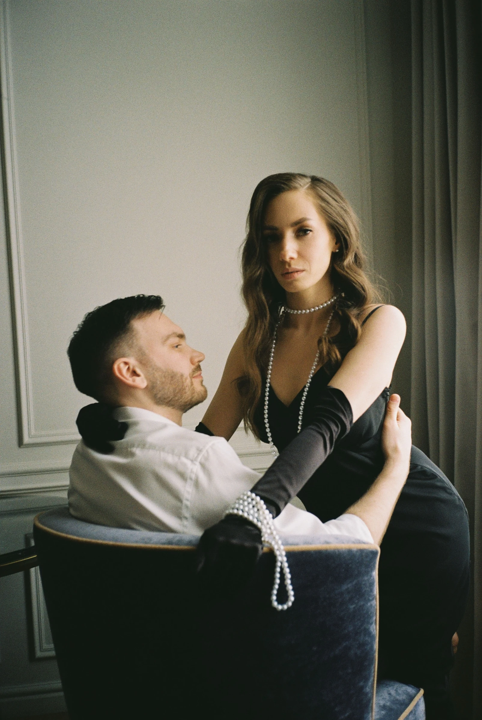 пара в стильных чёрных образах на постановочной love-story съёмке в интерьере