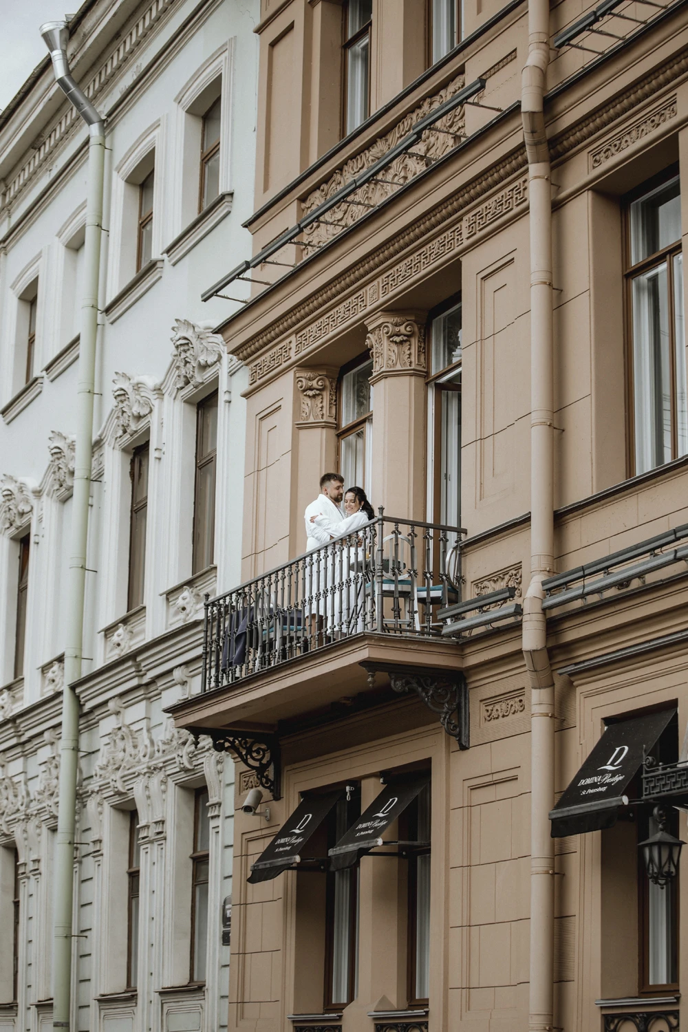 пара в белых халатах на балконе здания в историческом центре города