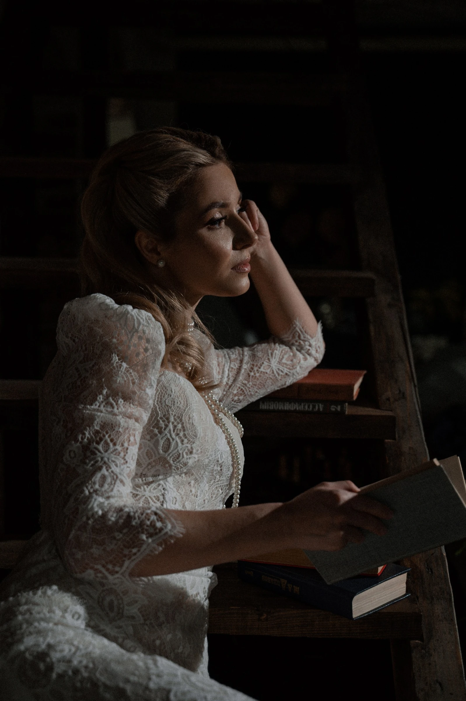 невеста в кружевном платье с книгой на фоне деревянных стеллажей