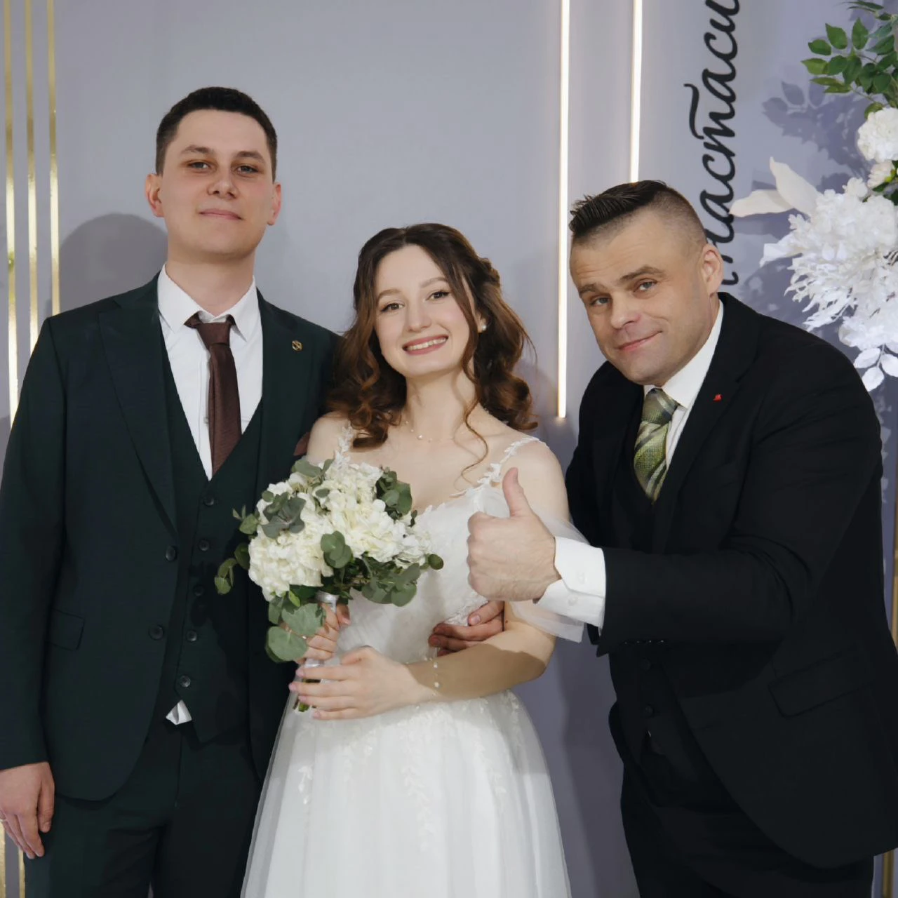ведущий показывает палец вверх рядом с молодожёнами у фотозоны