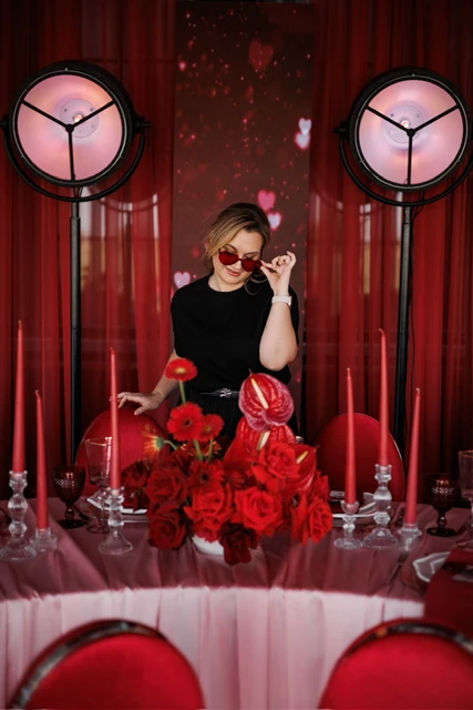 женщина у праздничного стола с красными свечами и розами