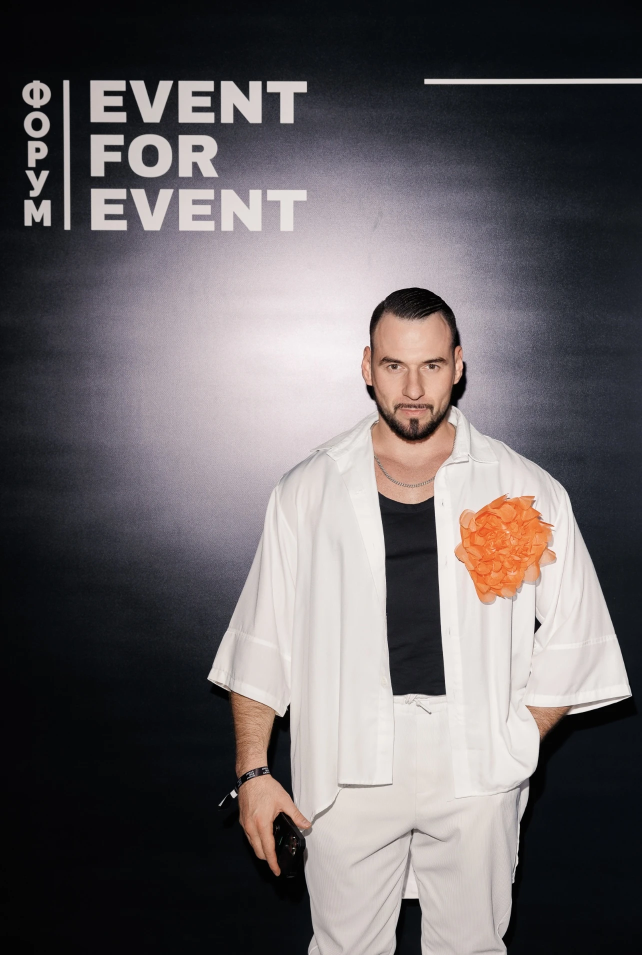 мужчина в белом костюме позирует на фотозоне ивент-форума Event for Event