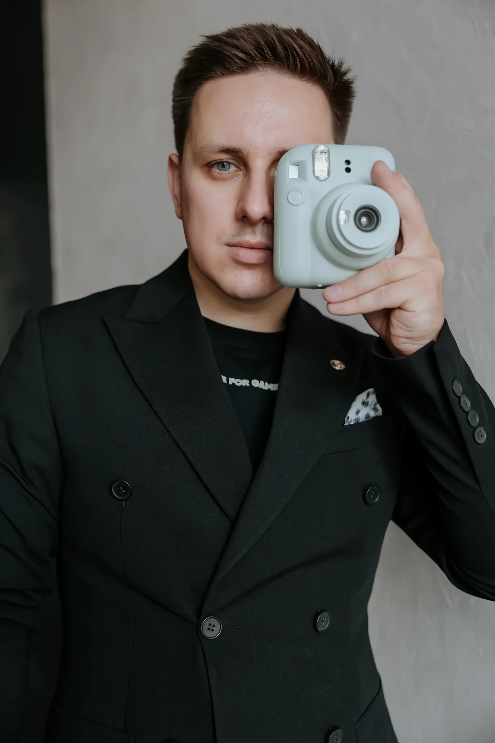 мужчина в костюме держит фотоаппарат у одного глаза