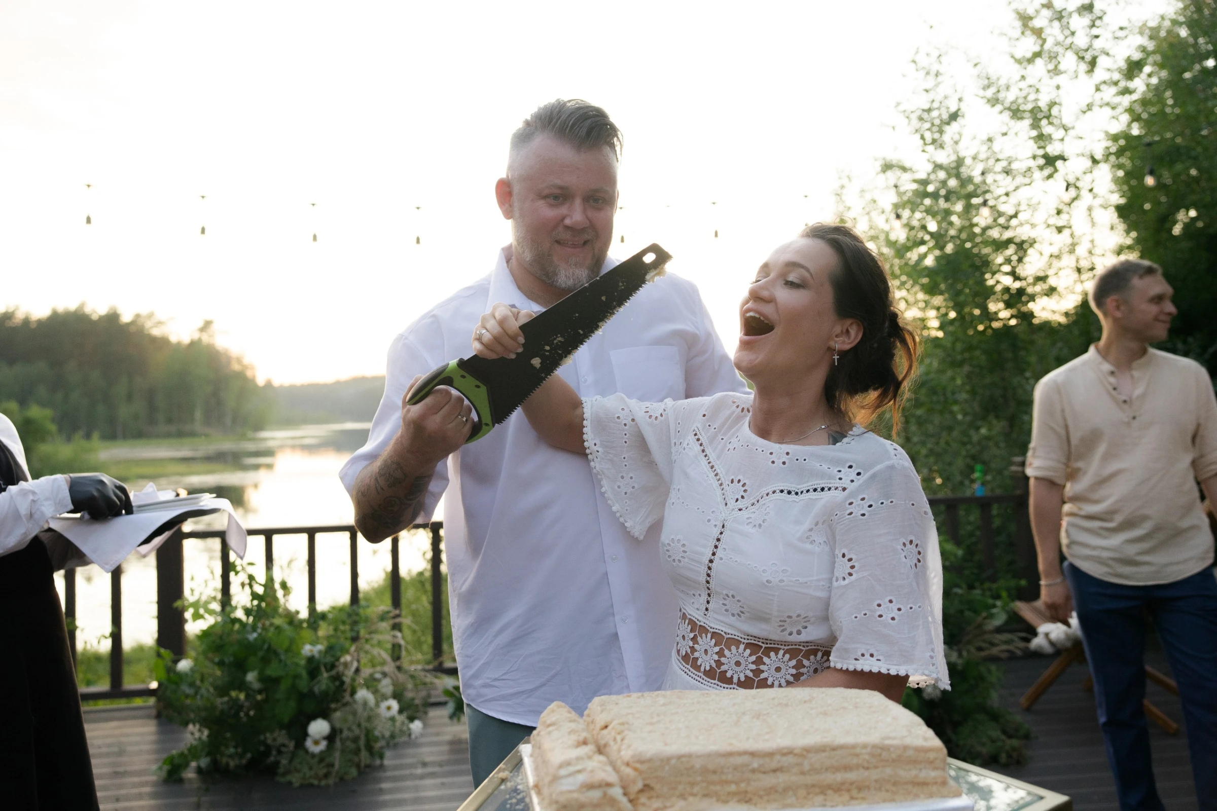 жених с бензопилой и смеющаяся невеста режут торт