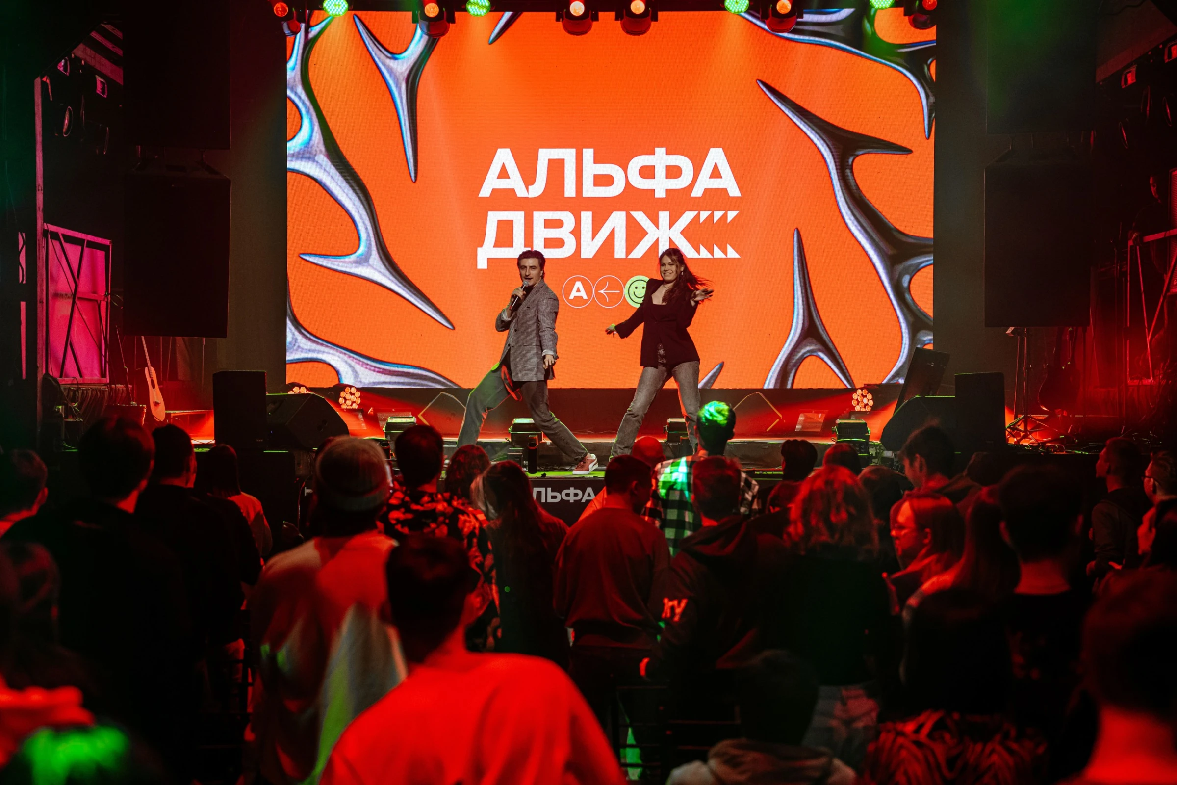 пара ведущих танцует на сцене перед толпой зрителей фестиваля