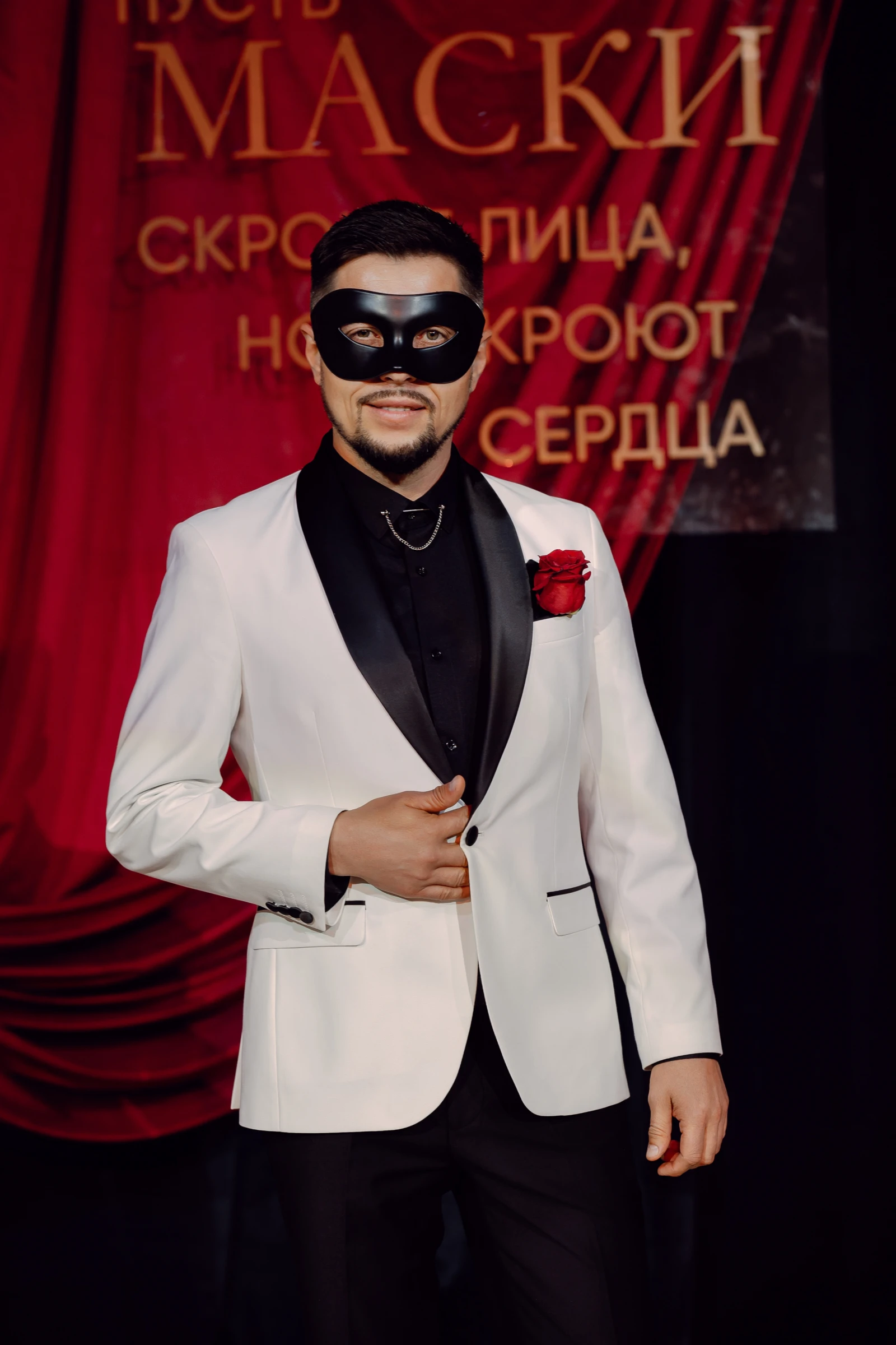 мужчина в чёрной маске у красного занавеса сцены