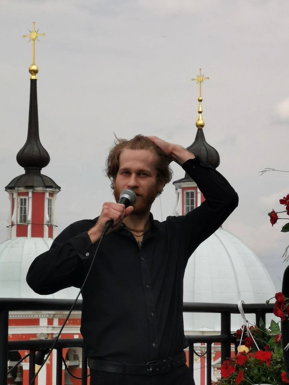 мужчина поправляет волосы с микрофоном на фоне куполов