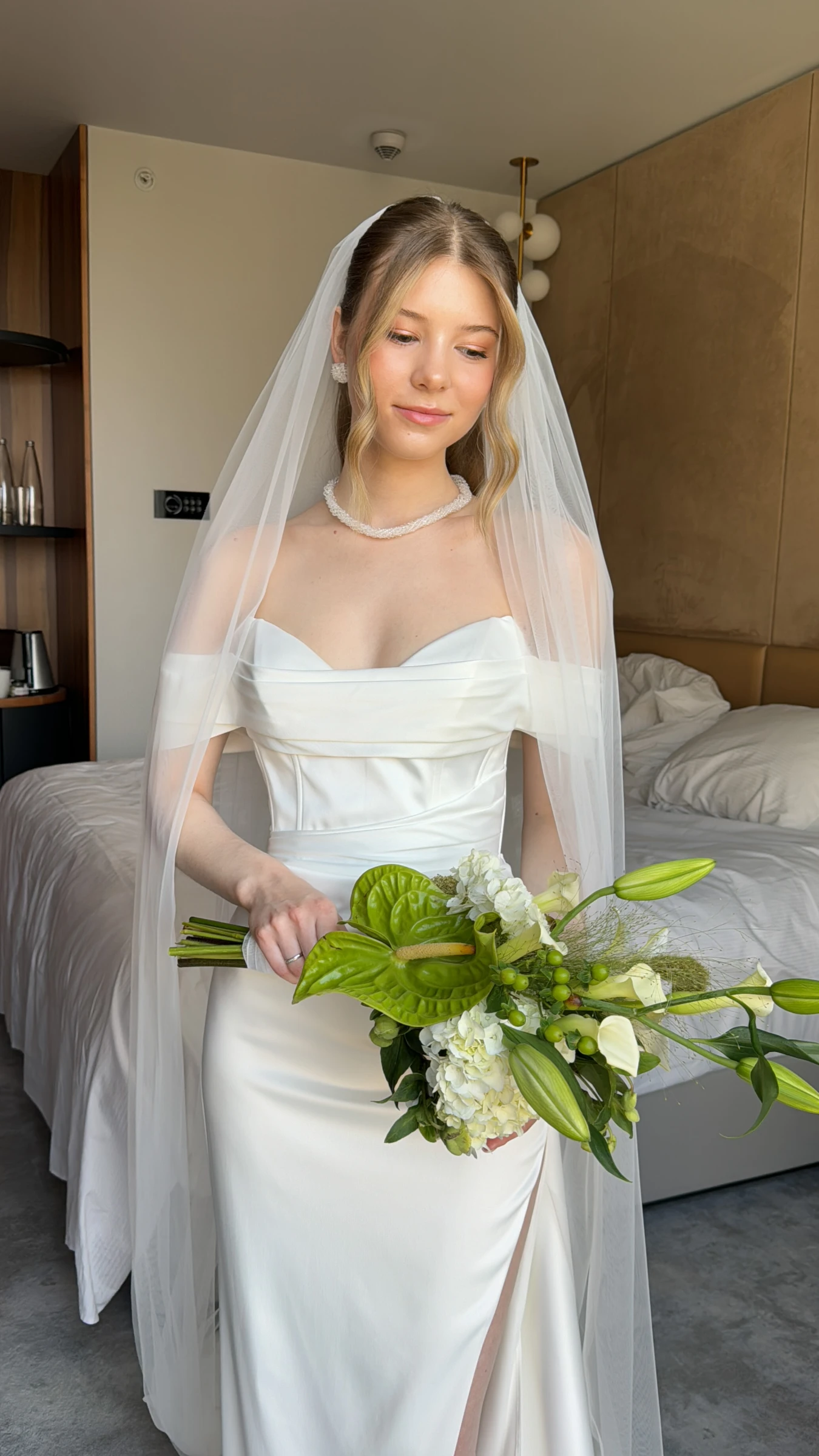 невеста в фате держит букет из белых цветов и зелени