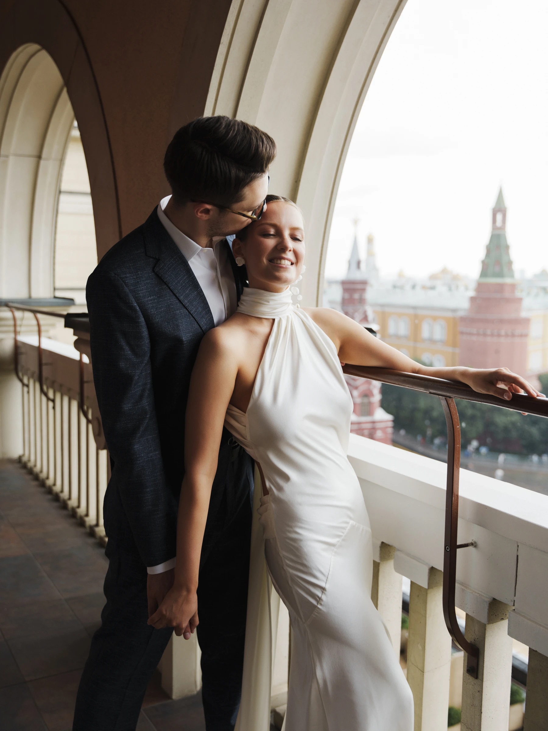 жених целует улыбающуюся девушку в лоб на фоне кремлёвских башен