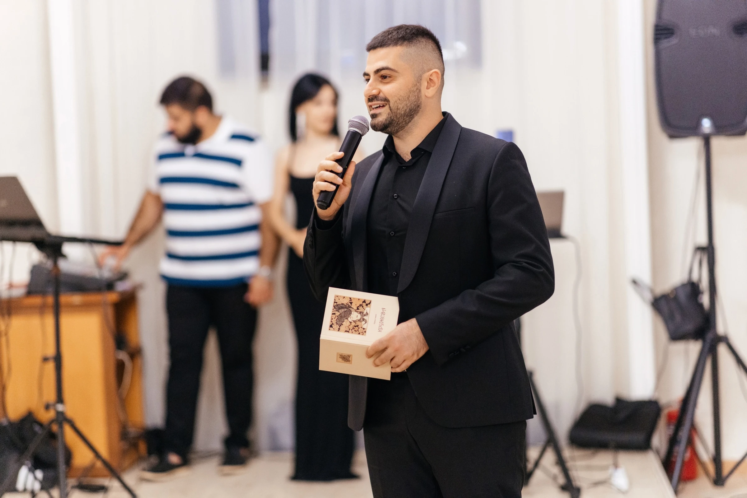 мужчина держит микрофон и подарочную коробку на сцене