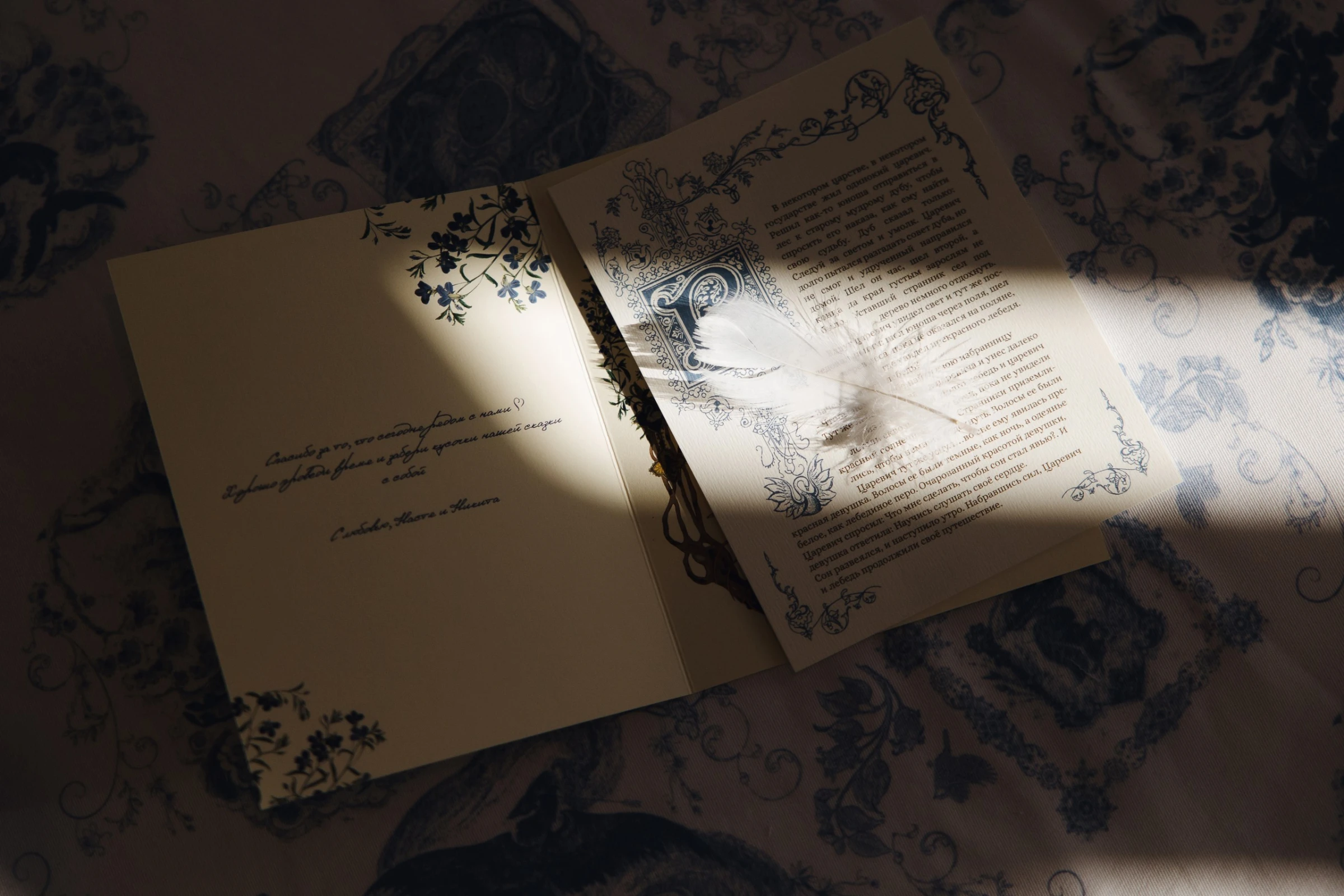 Раскрытая книга пожеланий с пером и цветочным узором в лучах солнечного света