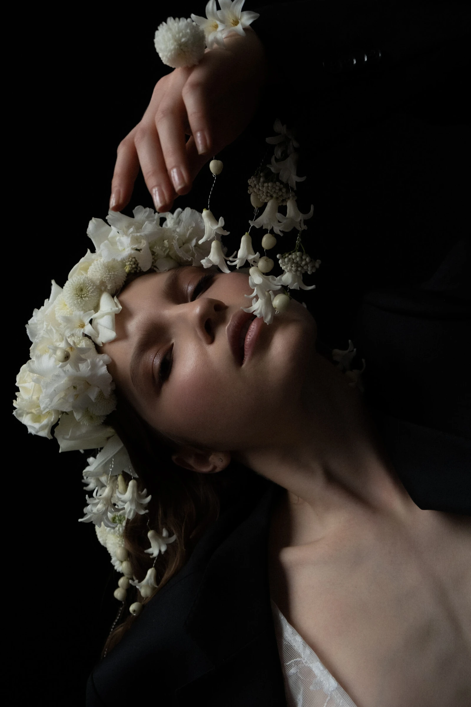 рука касается свисающих белых цветов на венке из хризантем