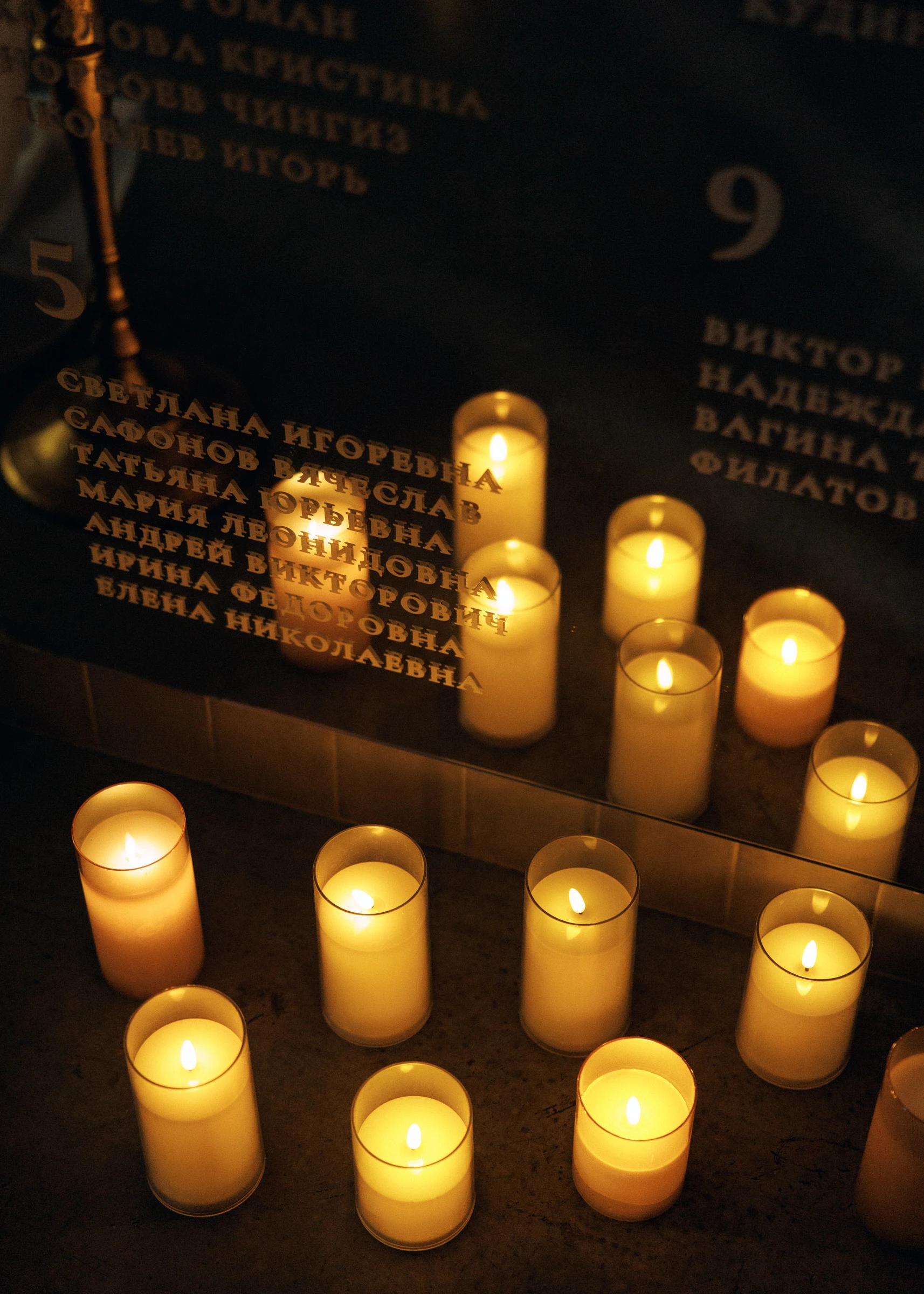 зажжённые свечи у памятной таблички с именами на свадебном банкете