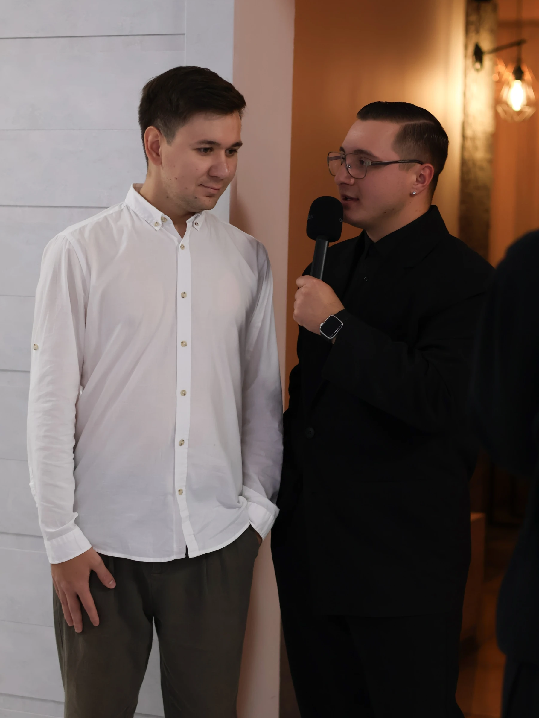 ведущий с микрофоном дружелюбно беседует с гостем перед началом свадьбы