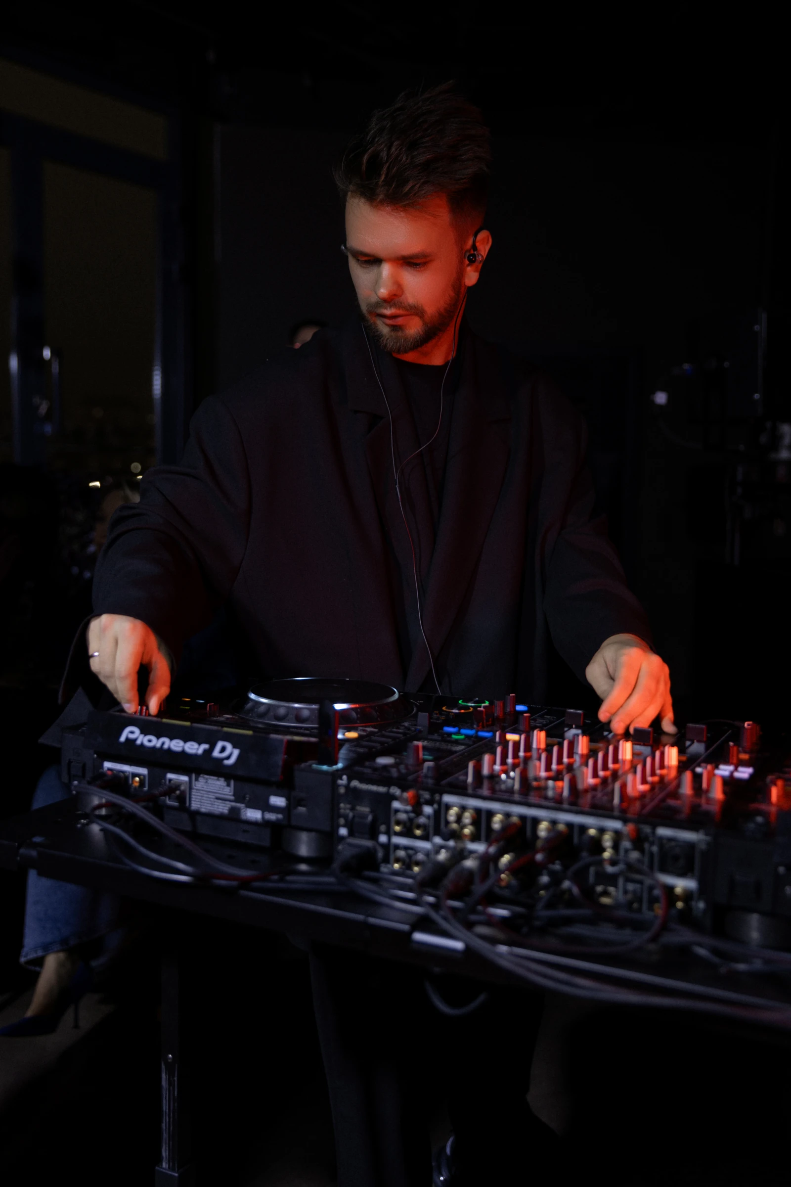 Диджей за микшером Pioneer DJ с красной подсветкой на приёме