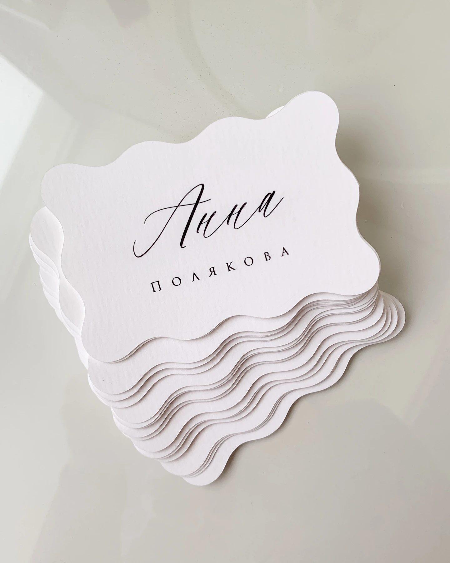 Белая карточка с именем Анна Полякова и волнистым фигурным краем