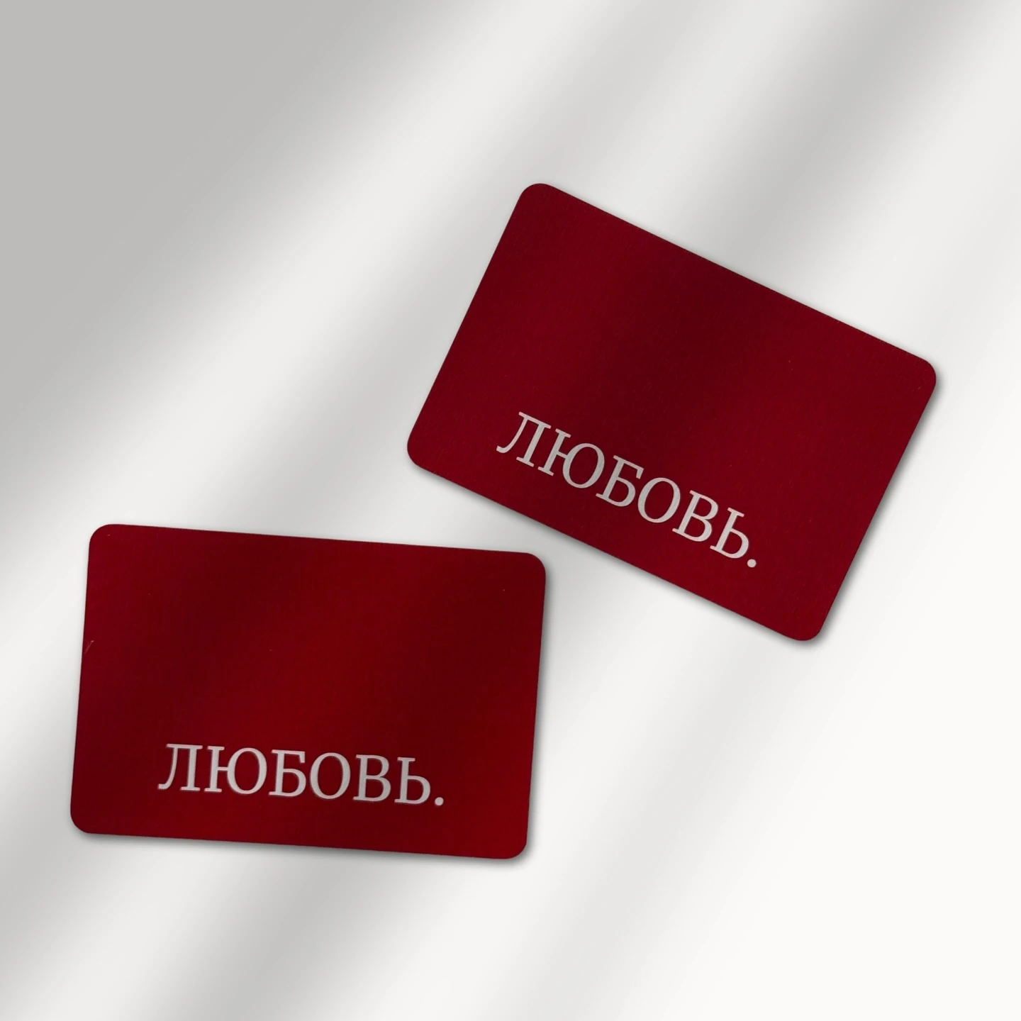 Металлические карточки бордового цвета с надписью Любовь на столе