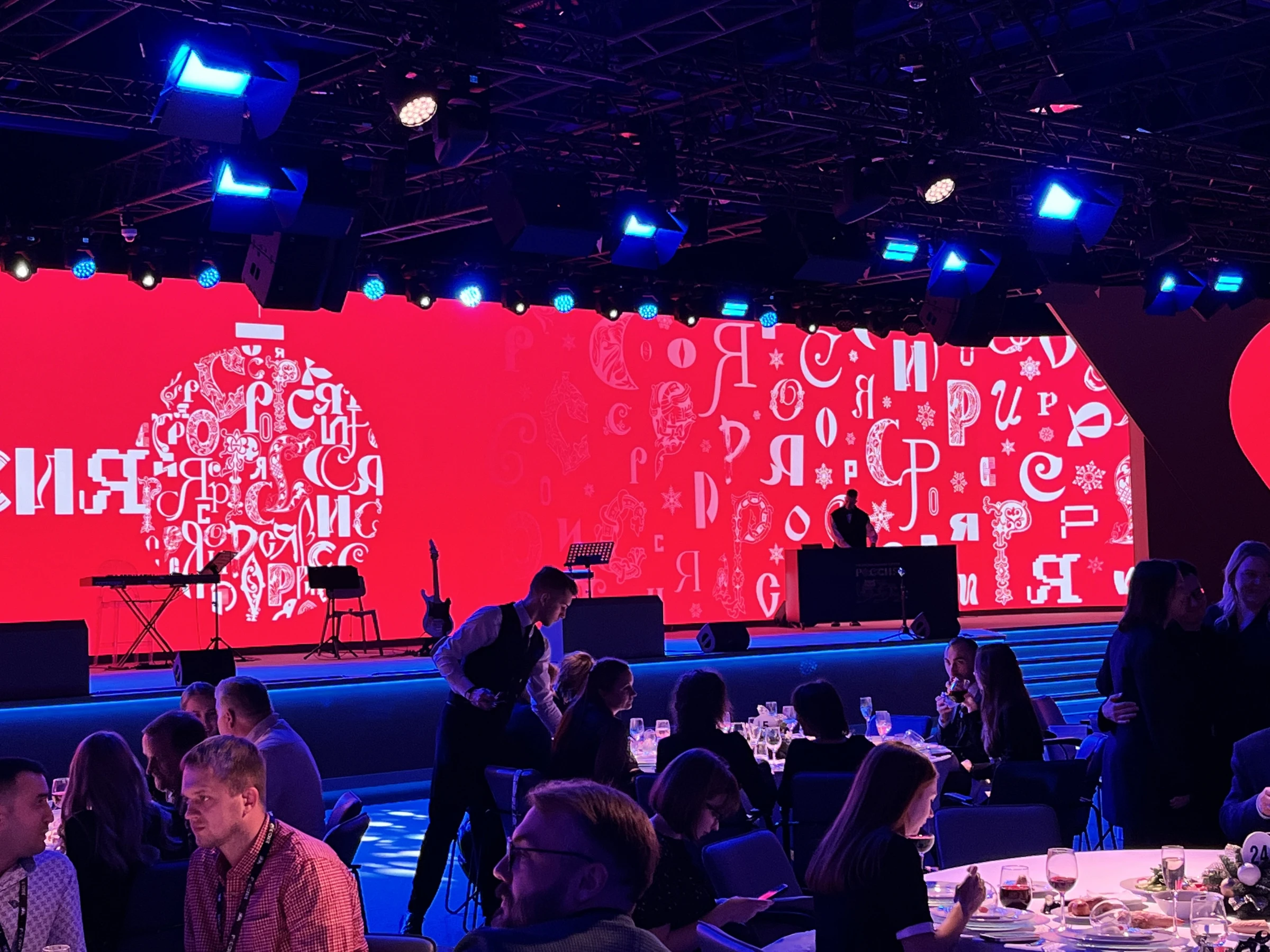 Сцена с диджей-пультом и красной LED-панелью на банкете гостей