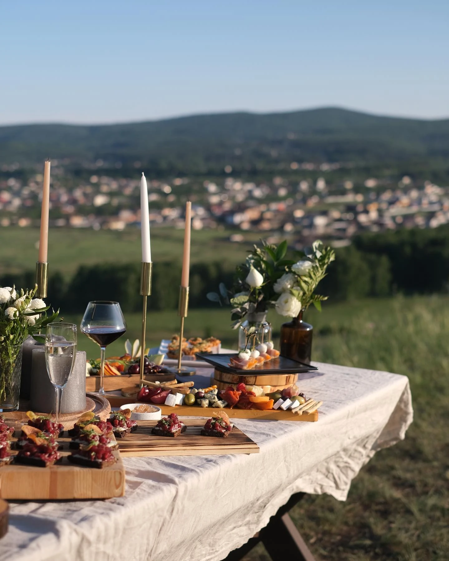 Фуршетный стол с закусками и свечами на холме с видом на долину