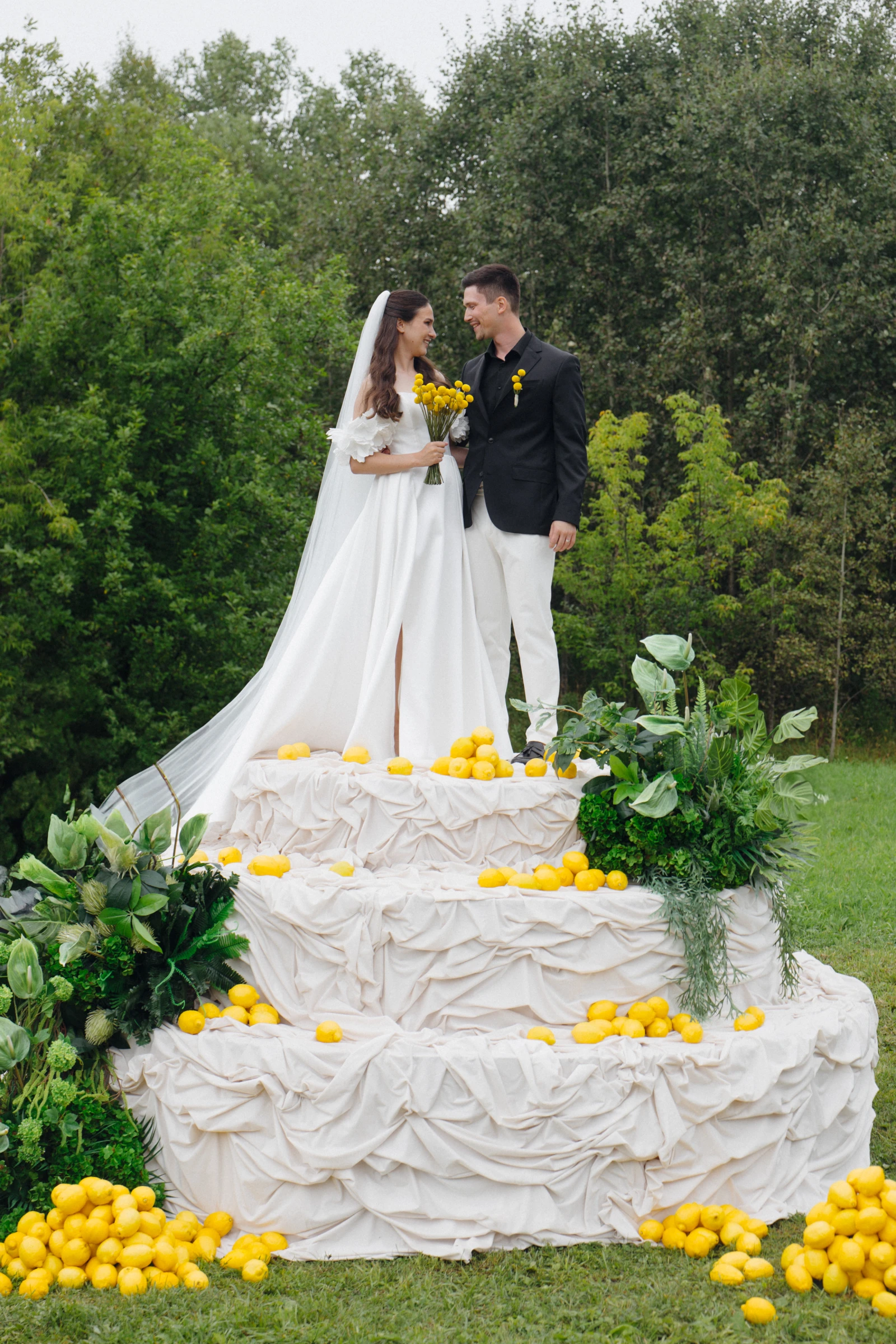 жених и невеста на декоративном торте с лимонами на фоне леса