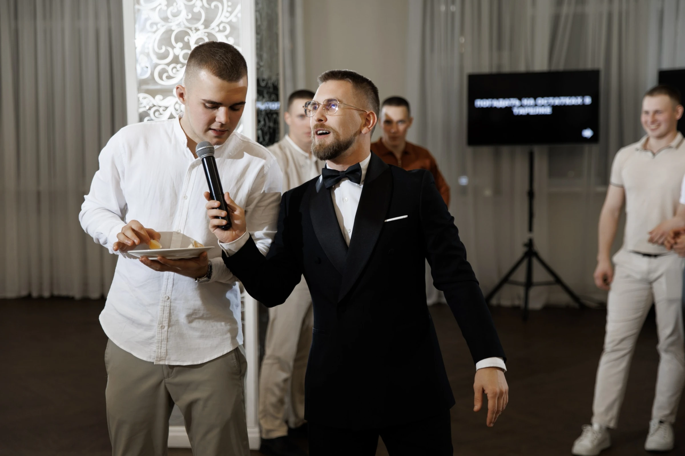 Ведущий держит микрофон у гостя во время конкурса на свадебном банкете