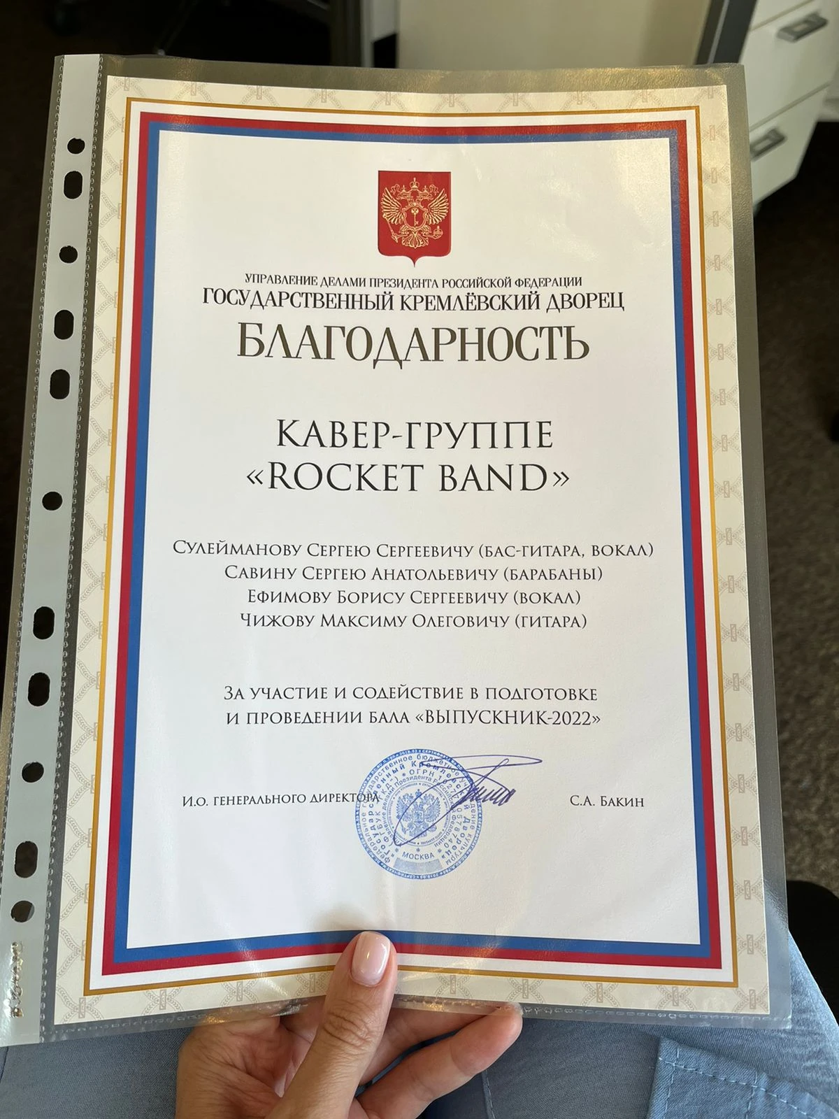 Трое музыкантов исполняют композицию на празднично украшенной сцене